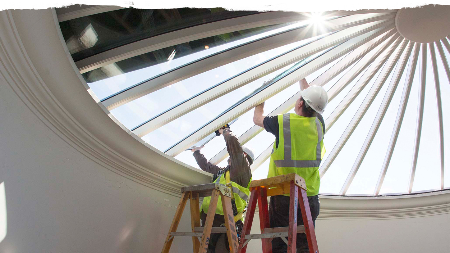 Two construction workers working on putting glass in the Rotunda dorm