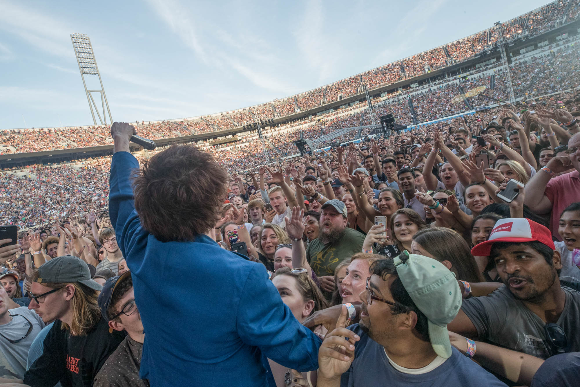 The singer from Cage the Elephant inside the crowd holding the microphone out to the crowd