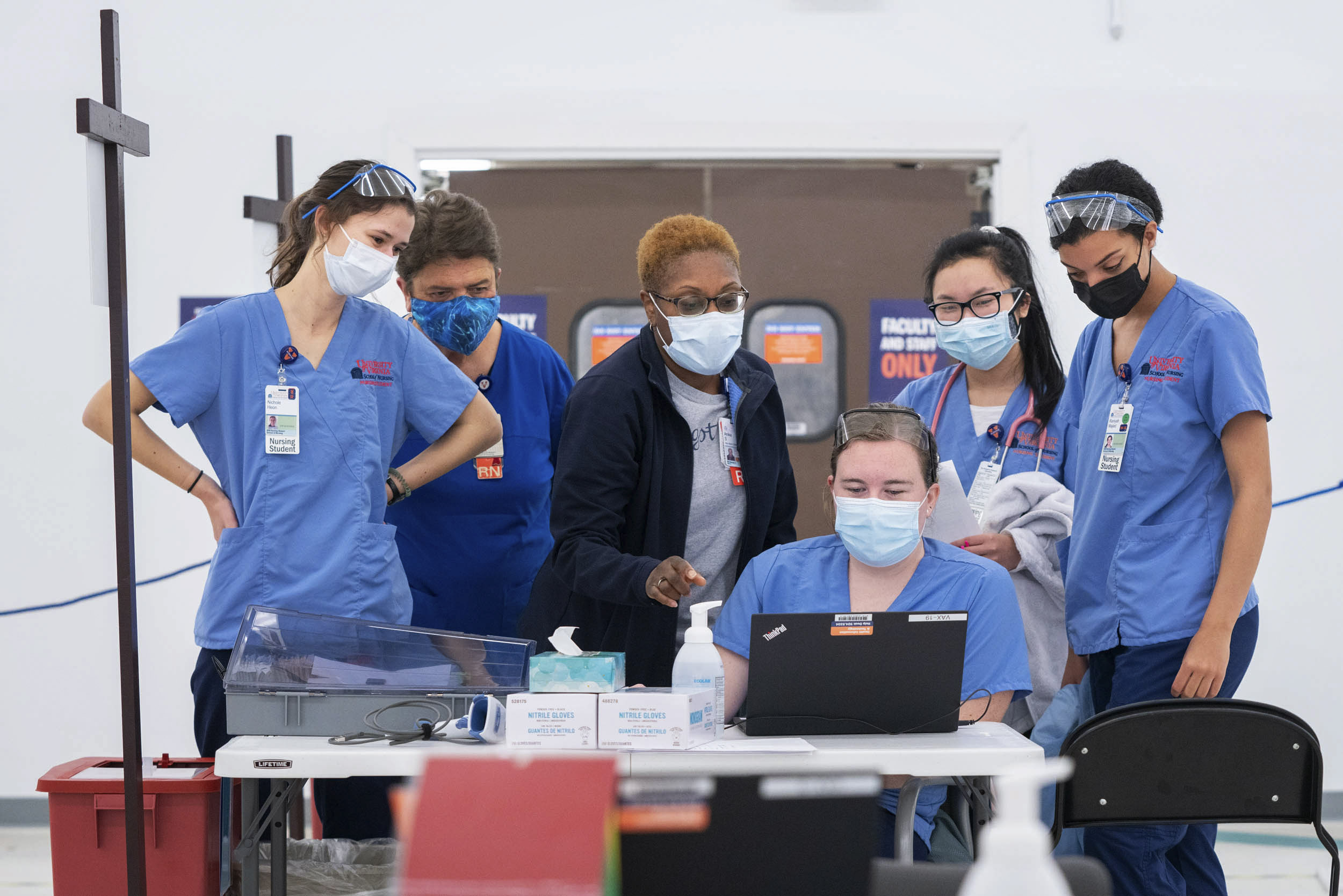 UVA Medical Students work with RN's on a computer at a covid vaccine clinic