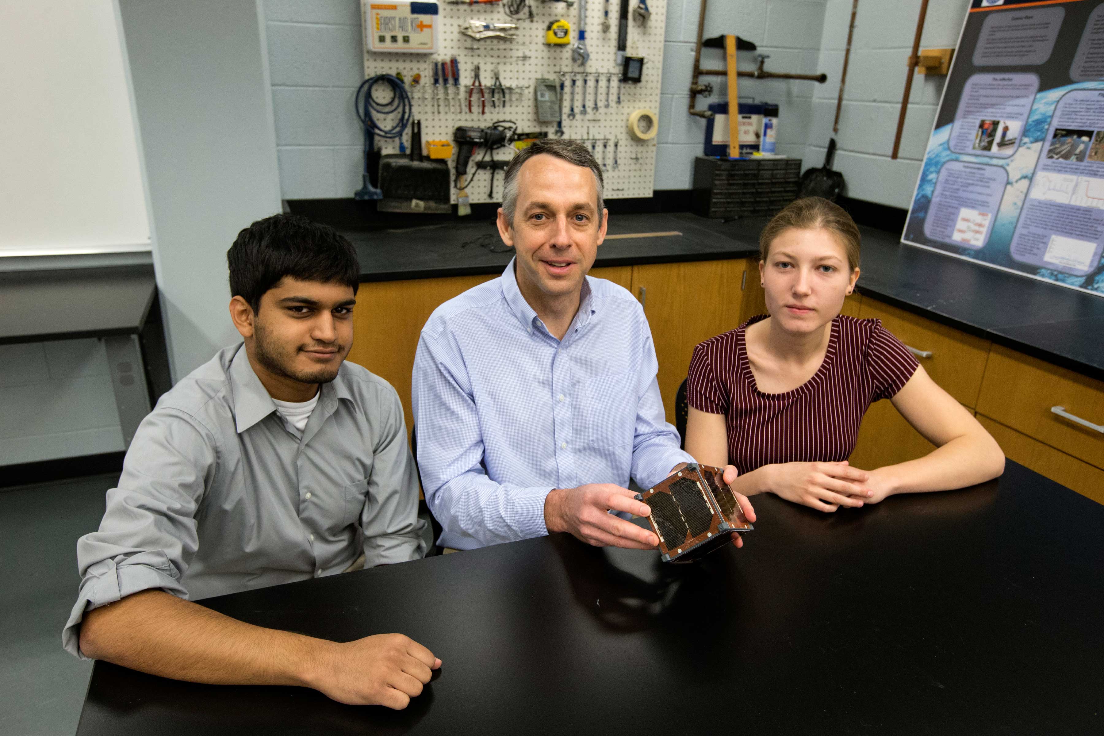 Aerospace engineering professor Chris Goyne, center, and students Chandrakanth “C.K.” Venigalla, left, and Robin Leiter are designing a mini satellite for a NASA experiment.