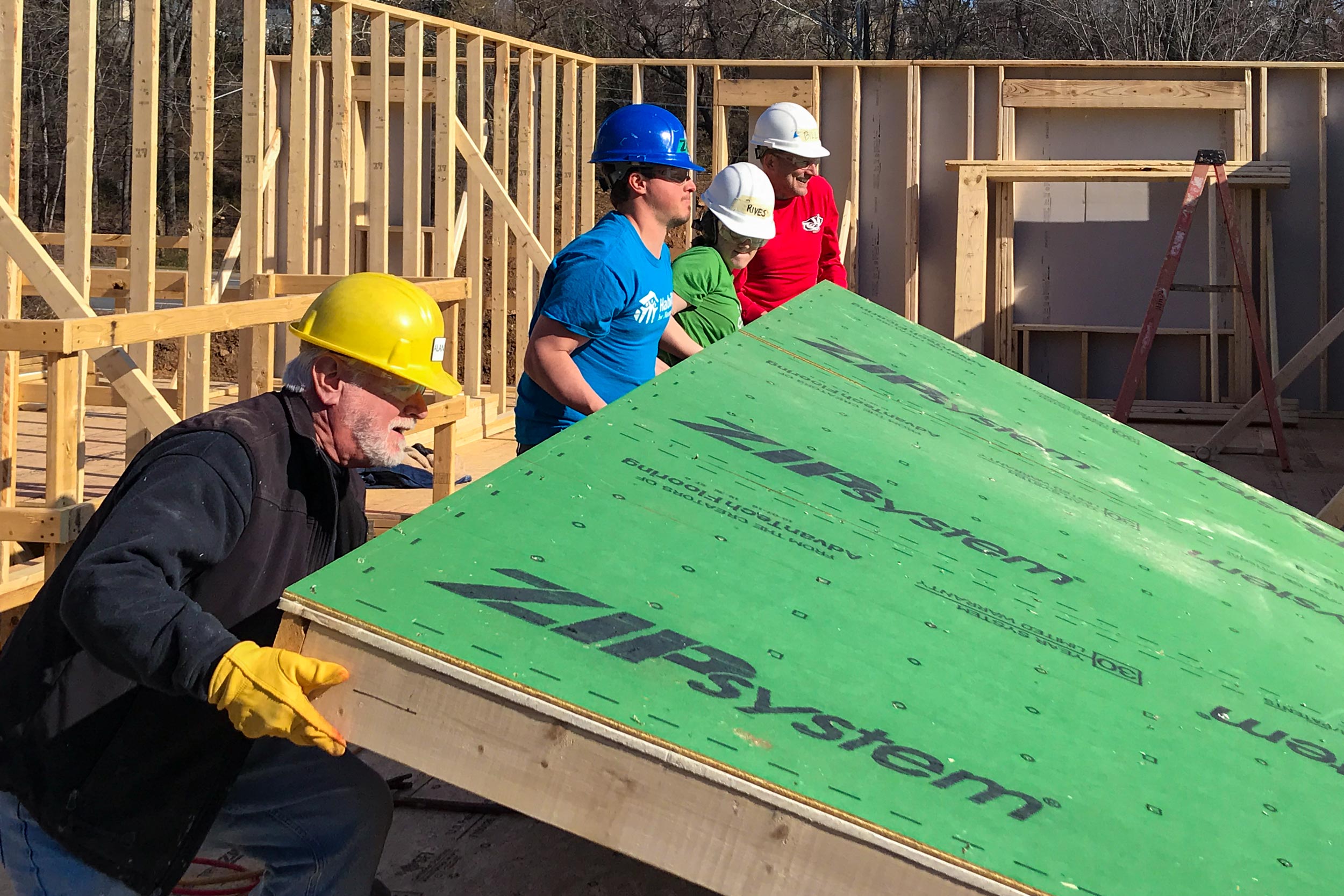 Volunteers help to raise a wall on a construction site