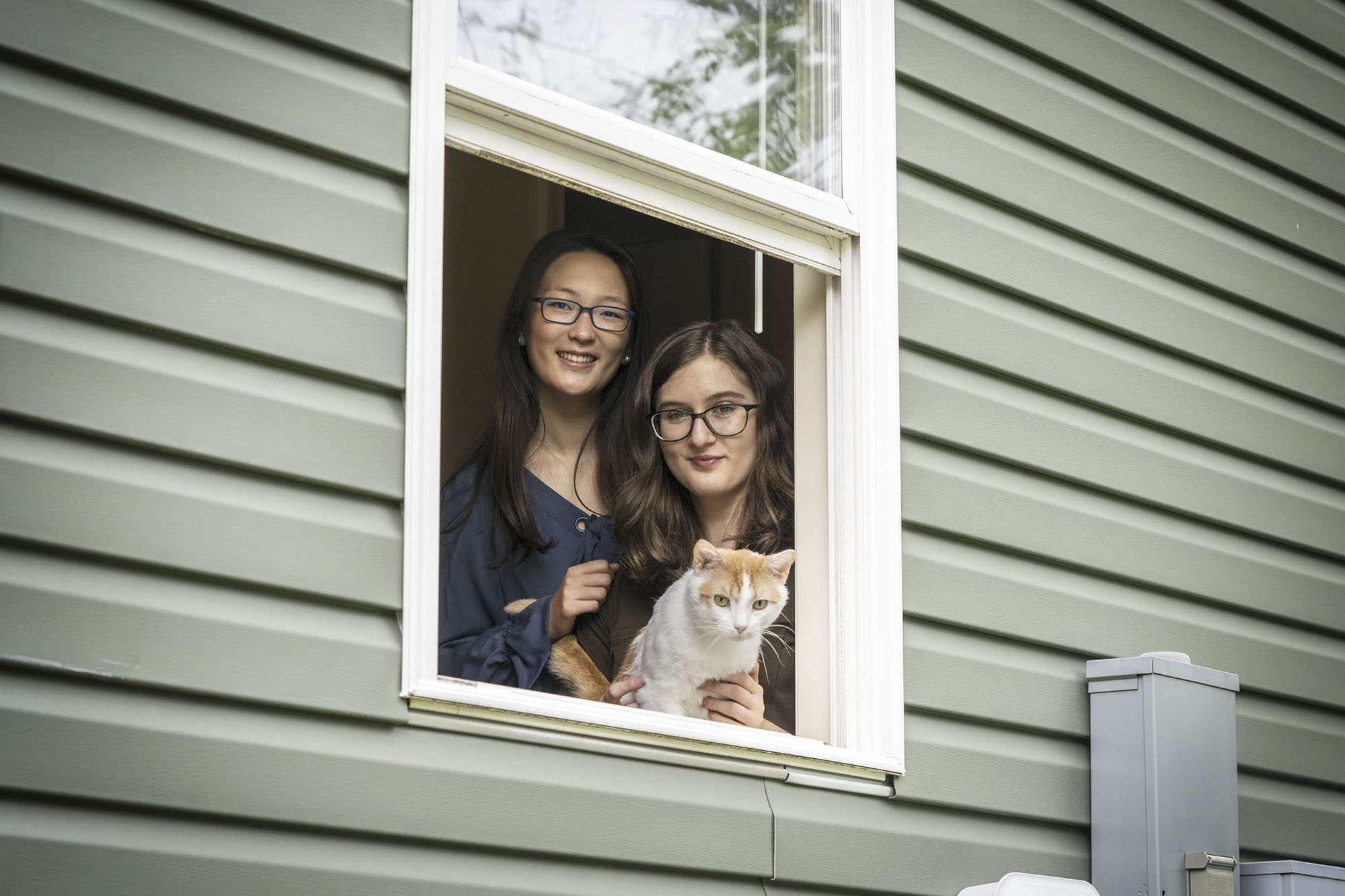 Two students looking out their window with their cat