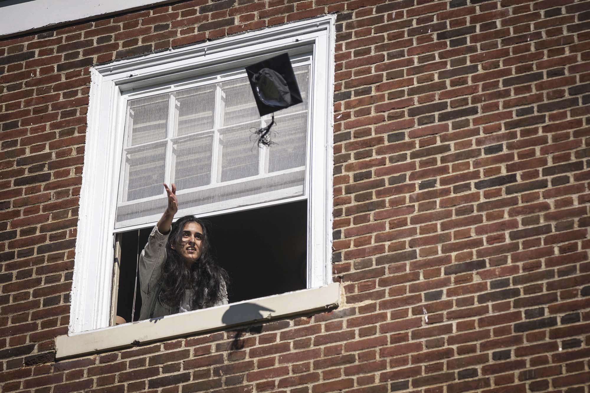Monica Ajay Jinsi throwing her graduation cap out of a window