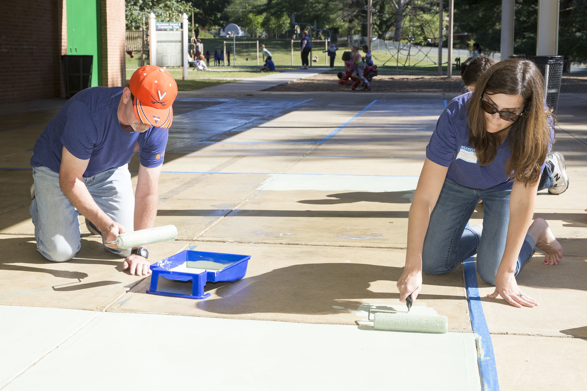 Employees from the College of Arts &amp; Sciences paint a huge game board on a concrete slab at Greenbrier Elementary School.