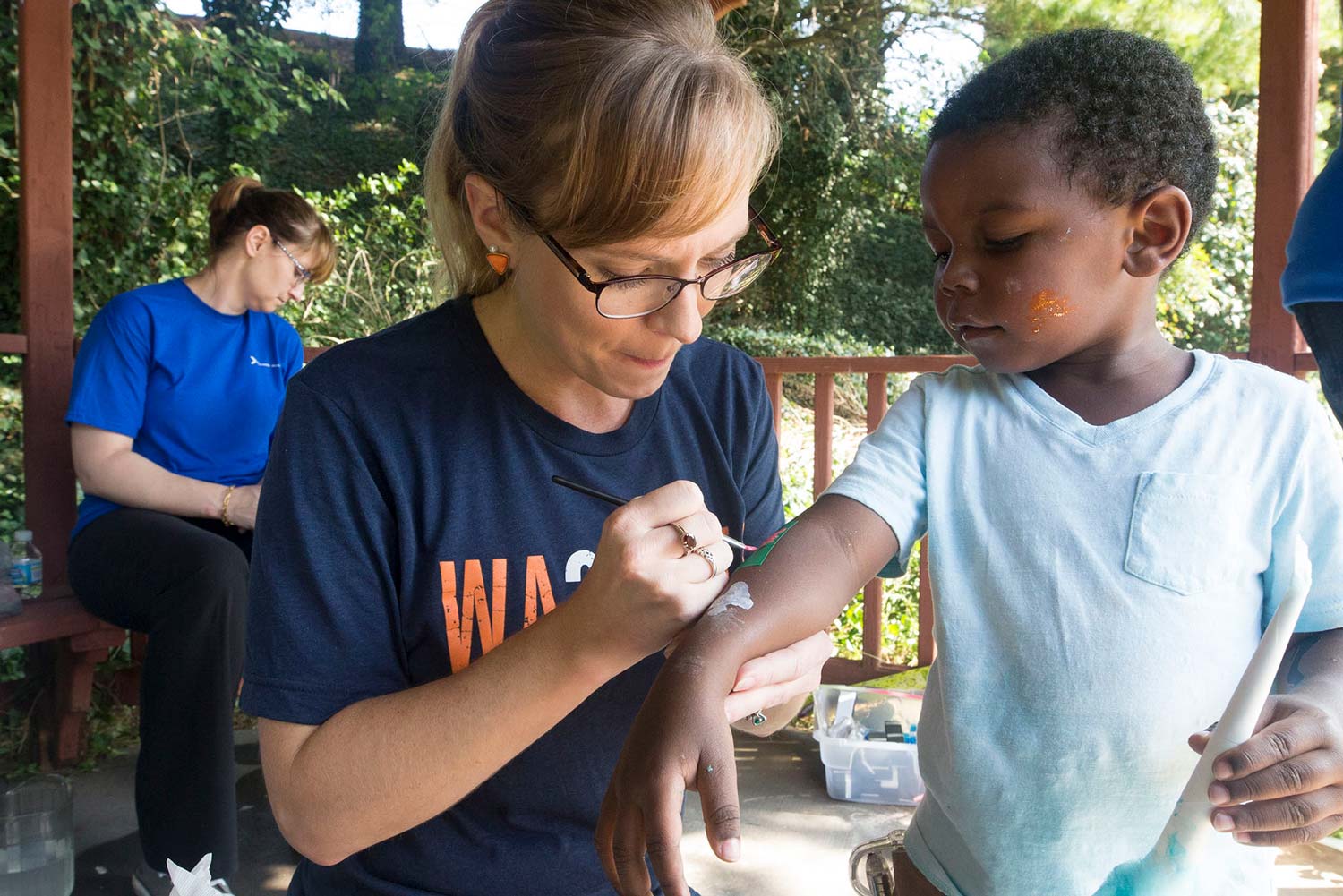 Amanda Deaton, painting on a little kids arm