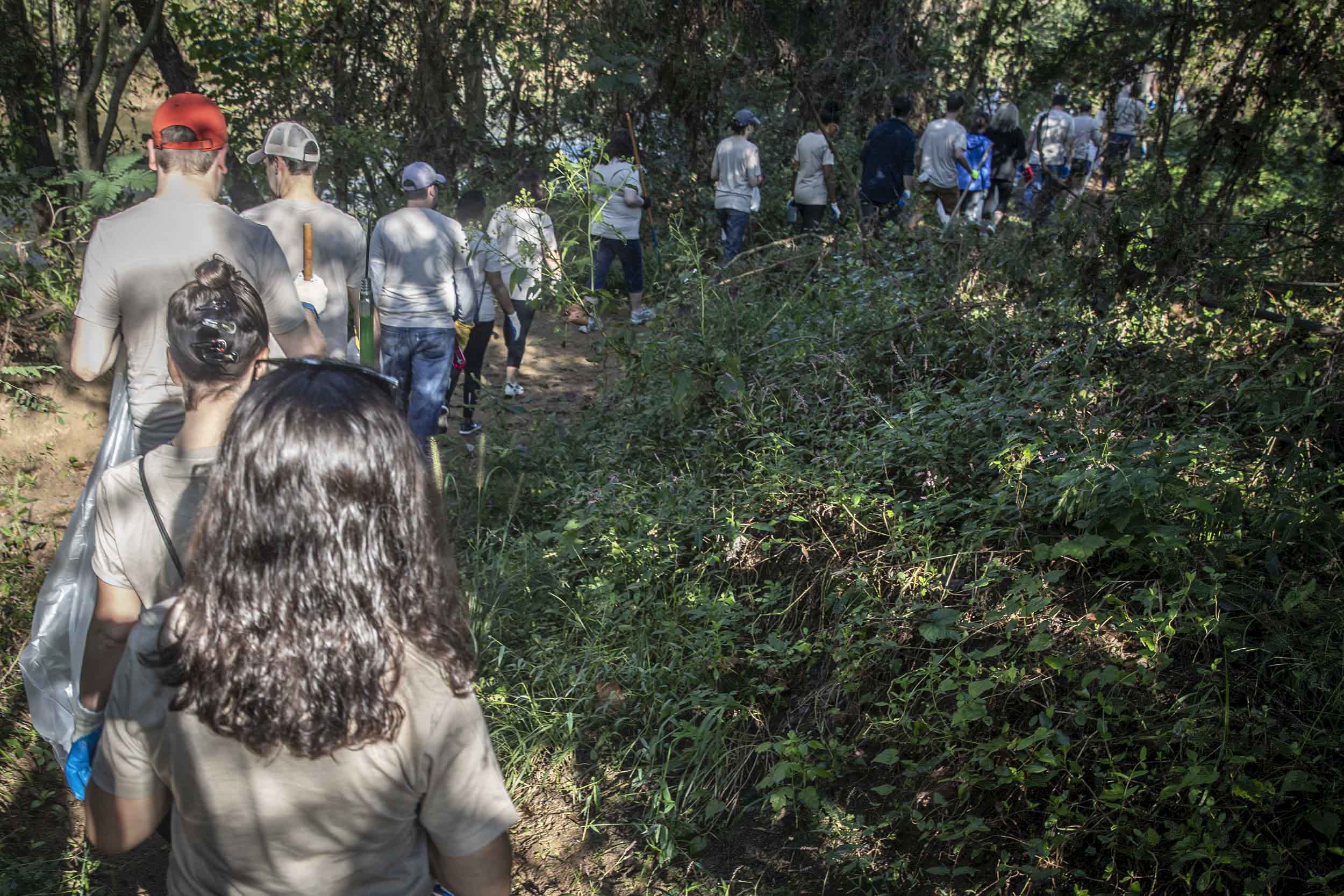 Line of Staff members walking on a trail carrying tools and trash bags