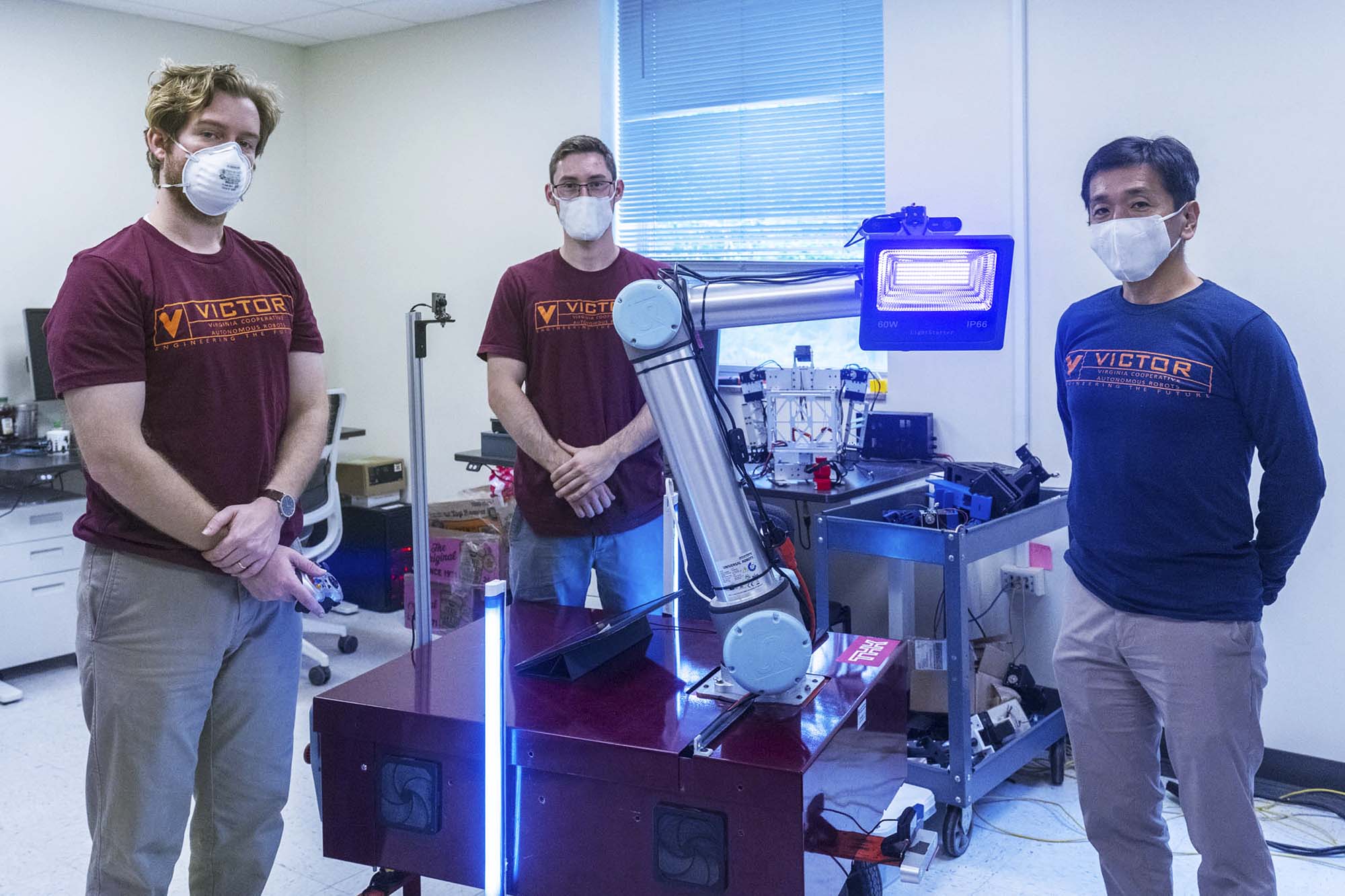 pencer Leamy and Dean Conte and professor Tomonari Furukawa stand next to their robot