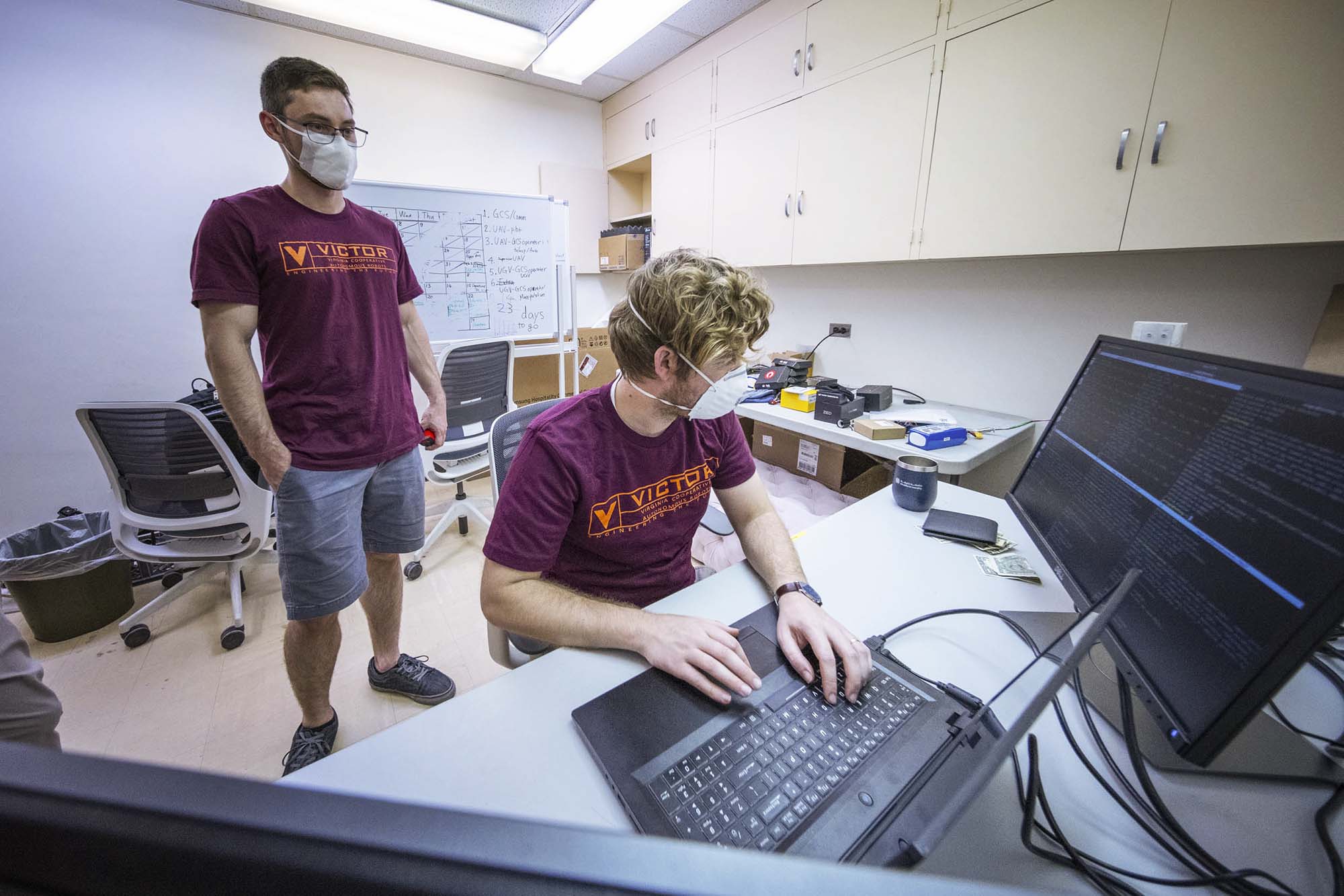 Conte and Leamy  watch a computer monitor to watch the progress of their robot