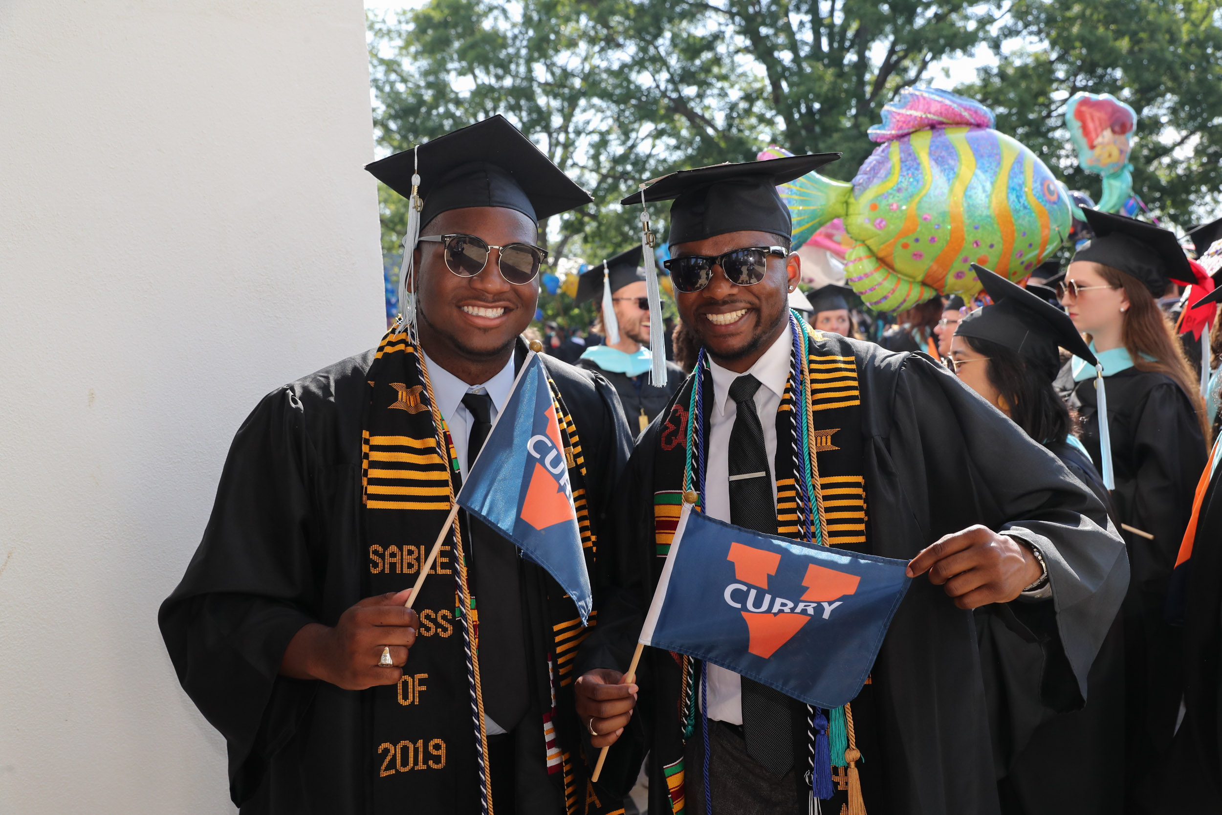 Graduates holding Curry flags smiling at the camera