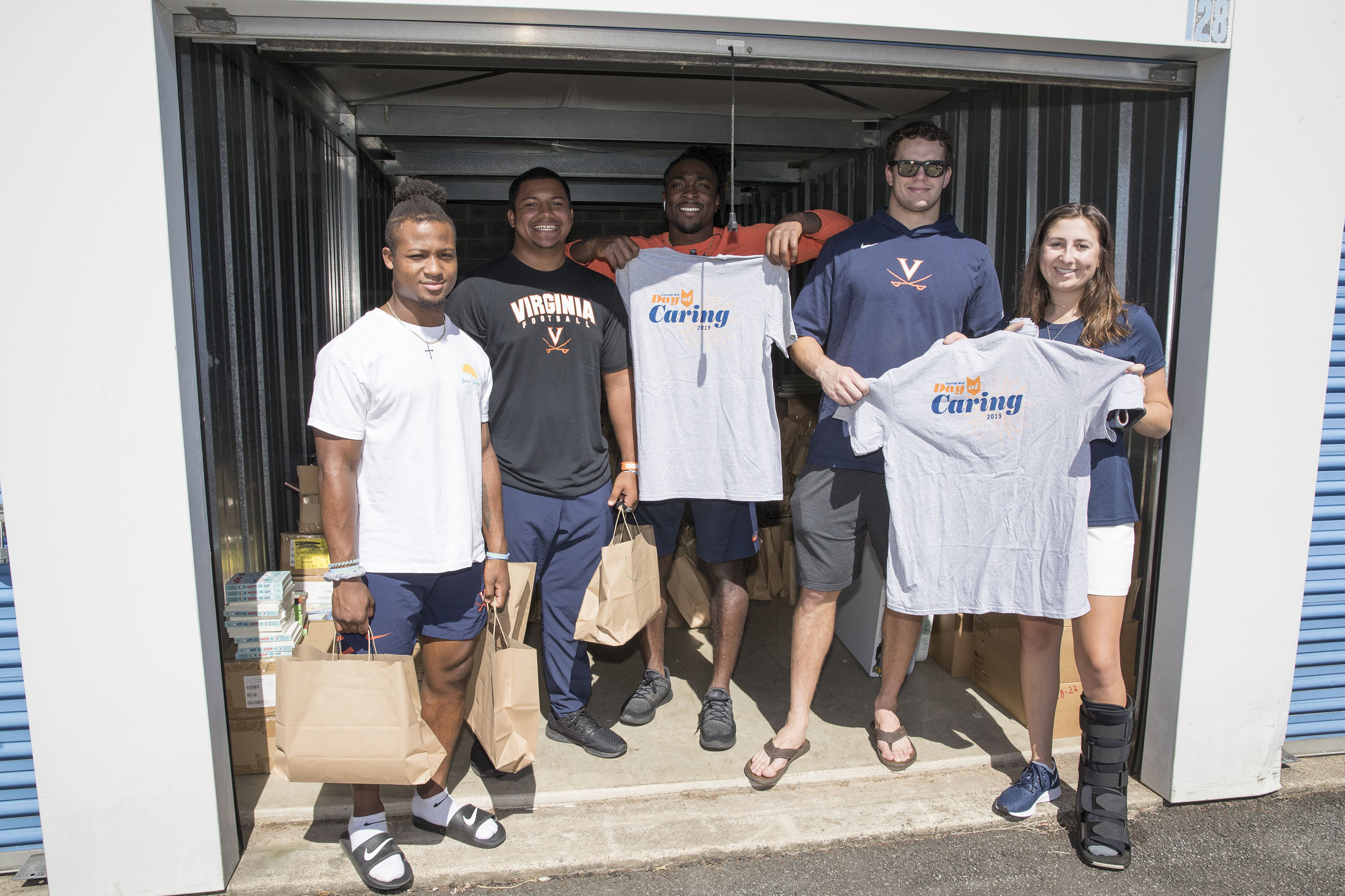 From left to right, football players Perris Jones, Dejuan Moore, Bryce Perkins and Tanner Cowley, and golfer Sky Sload stand in the back of a truck with bags of books