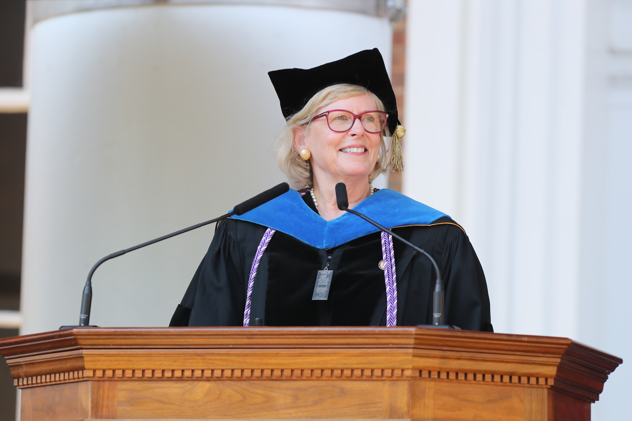 Dorrie Fontaine standing at the podium in cap and gown giving a speech to the graduating class