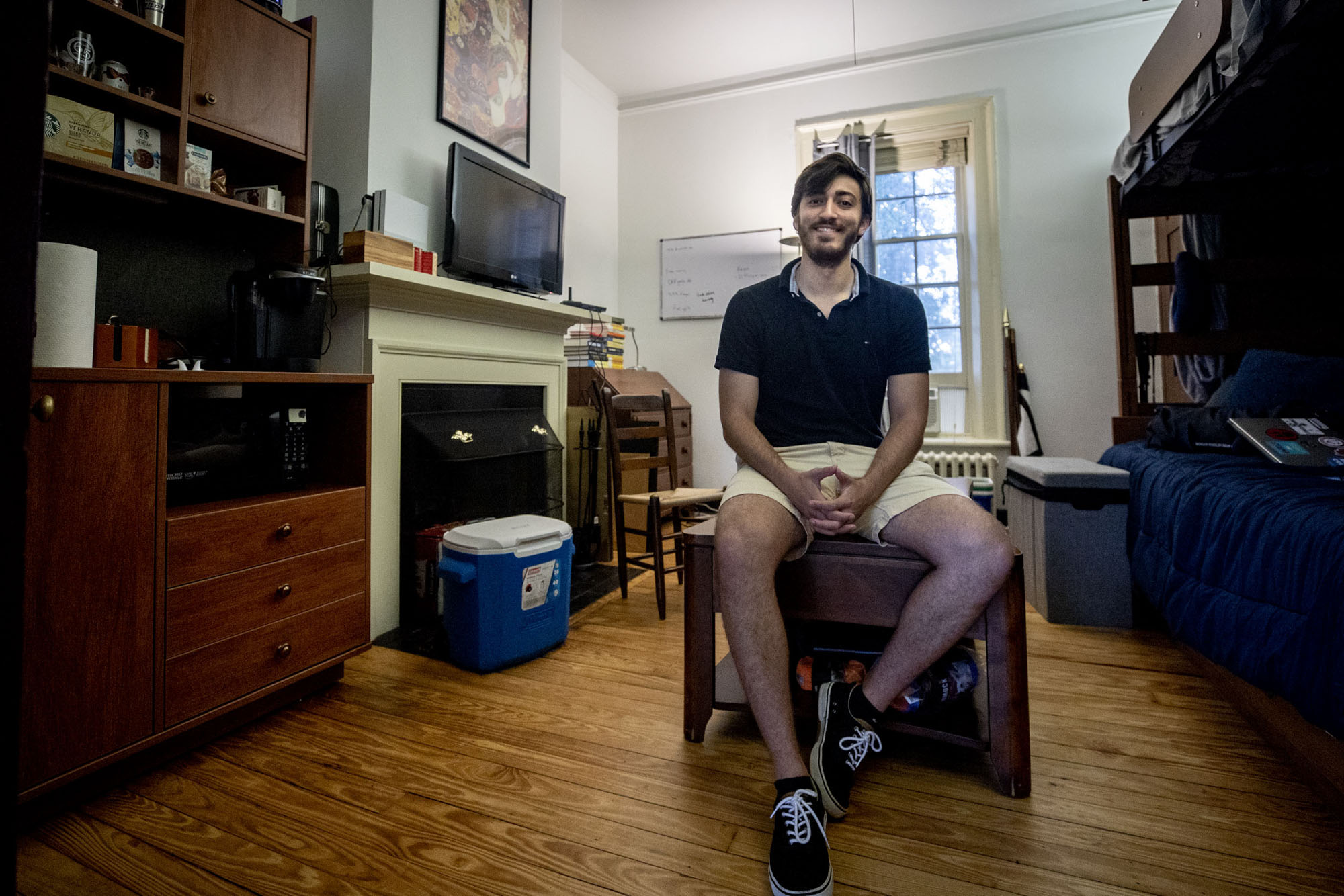 Ethan Zell sits on a coffee table in his room on the Lawn