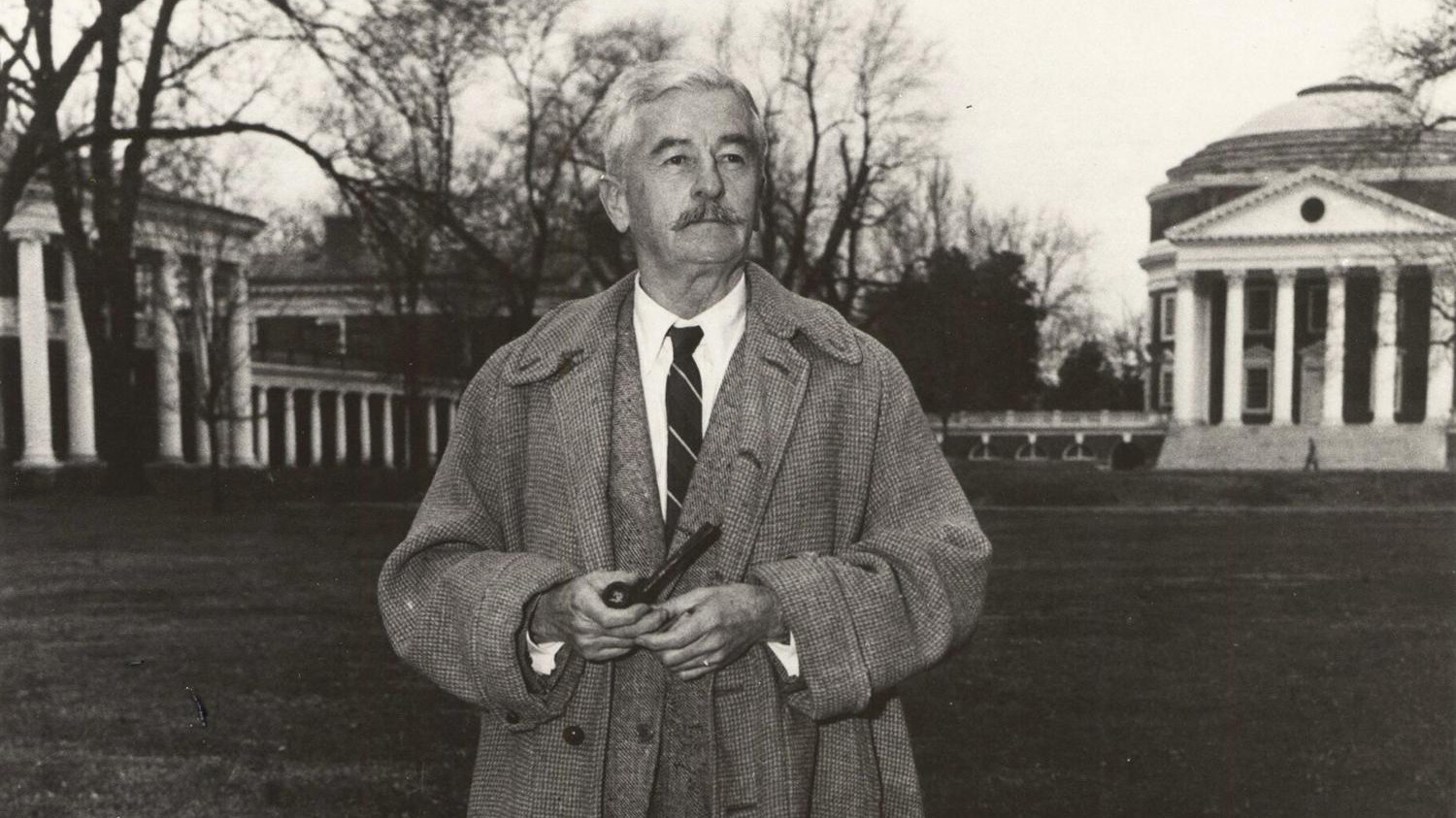 Faulkner standing on the lawn with a pipe. black and white image
