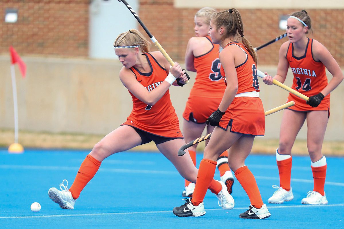 Womans Field Hockey team hitting a ball on the field