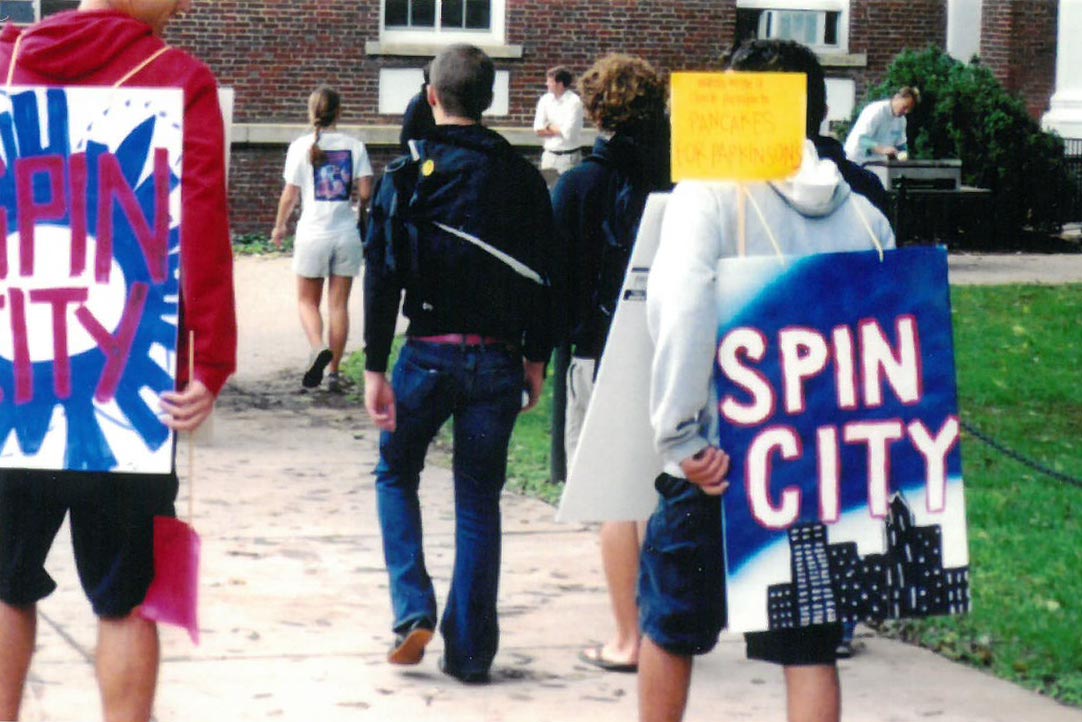 Students holding signs that read Spin City