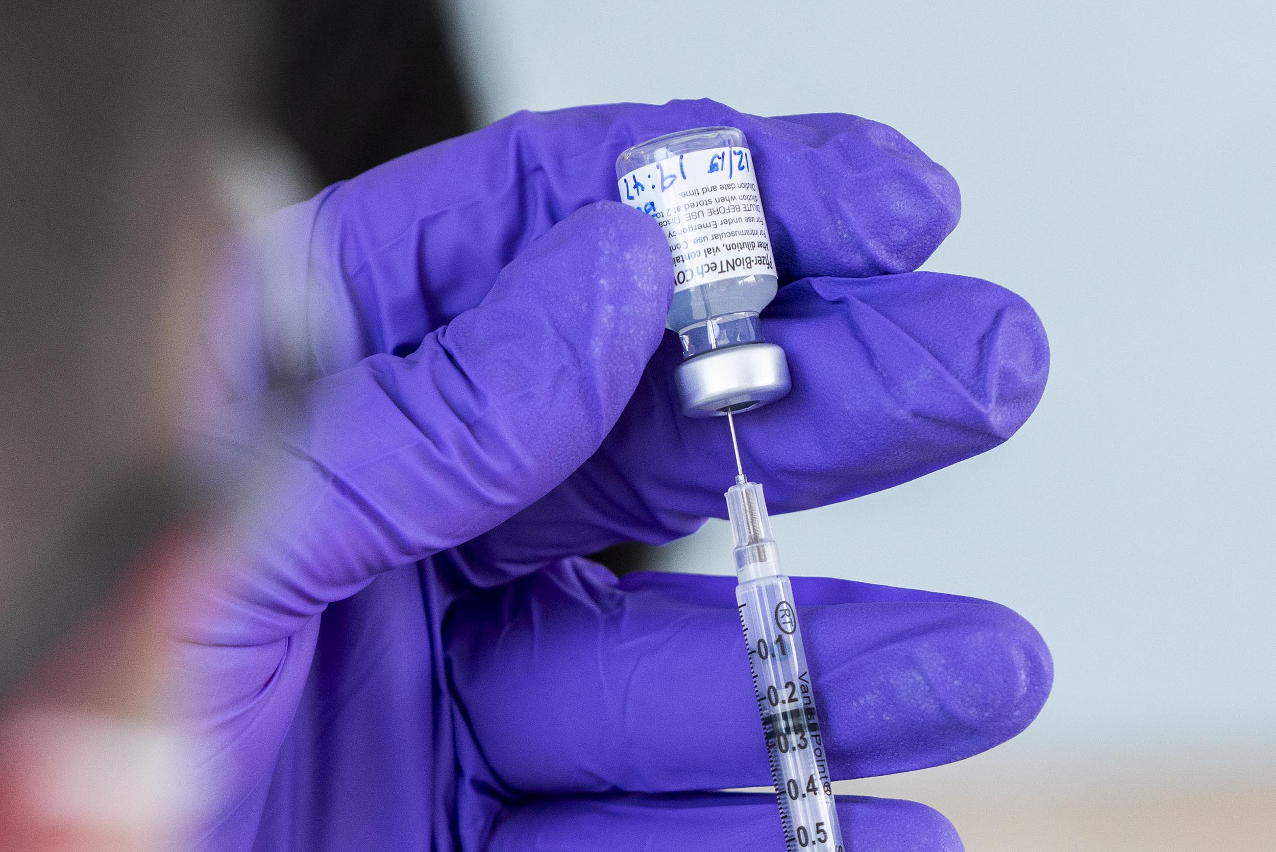 Healthcare worker drawing up Pfizer vaccine in a syringe