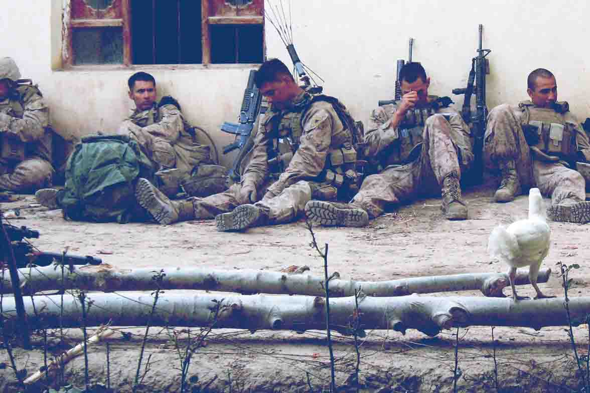 Soldiers sitting on the ground in a war zone