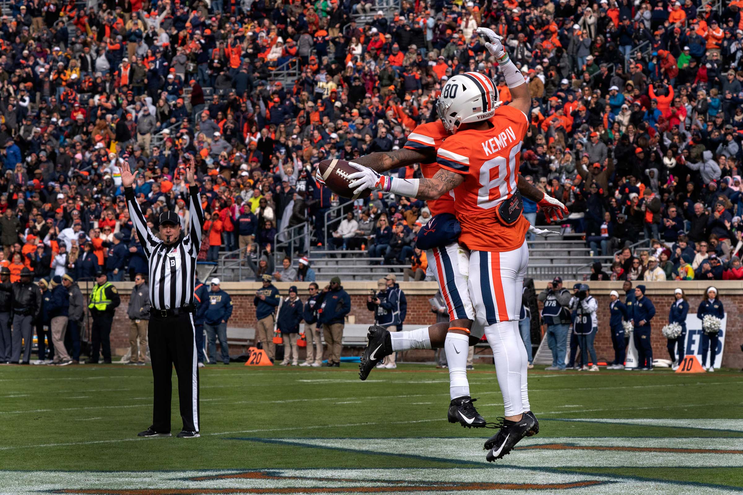 Two UVA players jump in the air and hit each others chest while in the endzone