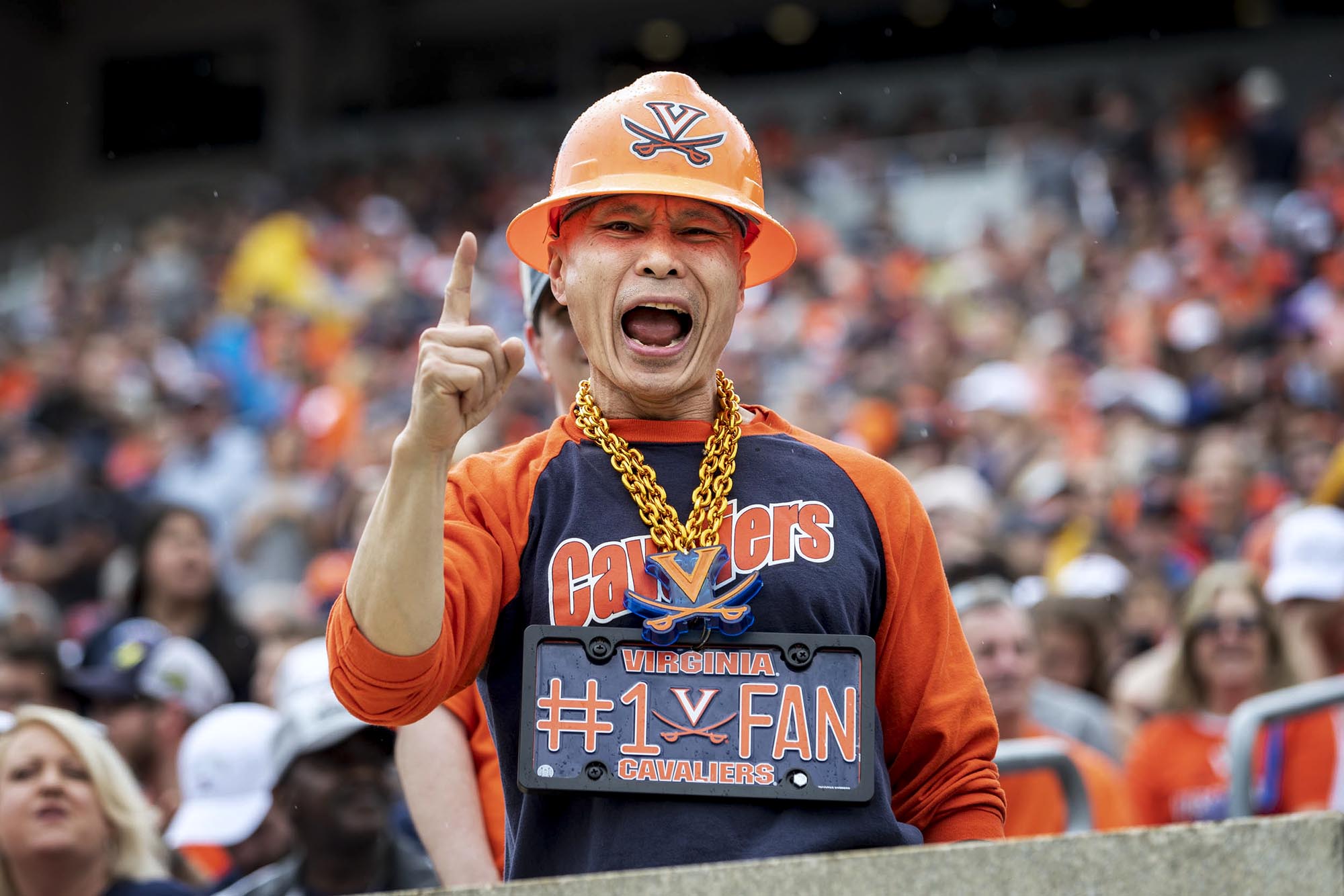 Som Patasomcit decked out in UVA gear screaming during a football game