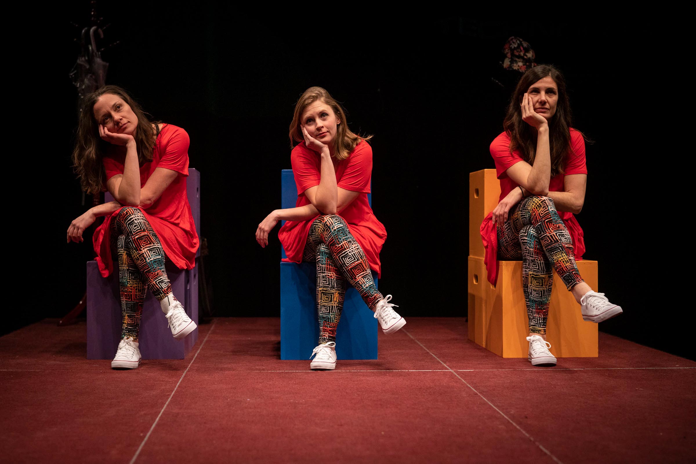 left to right, Melissa Frost, Sarah Rabke and Alicia Lopez Operé sit on multicolored boxes with their head in their right hand