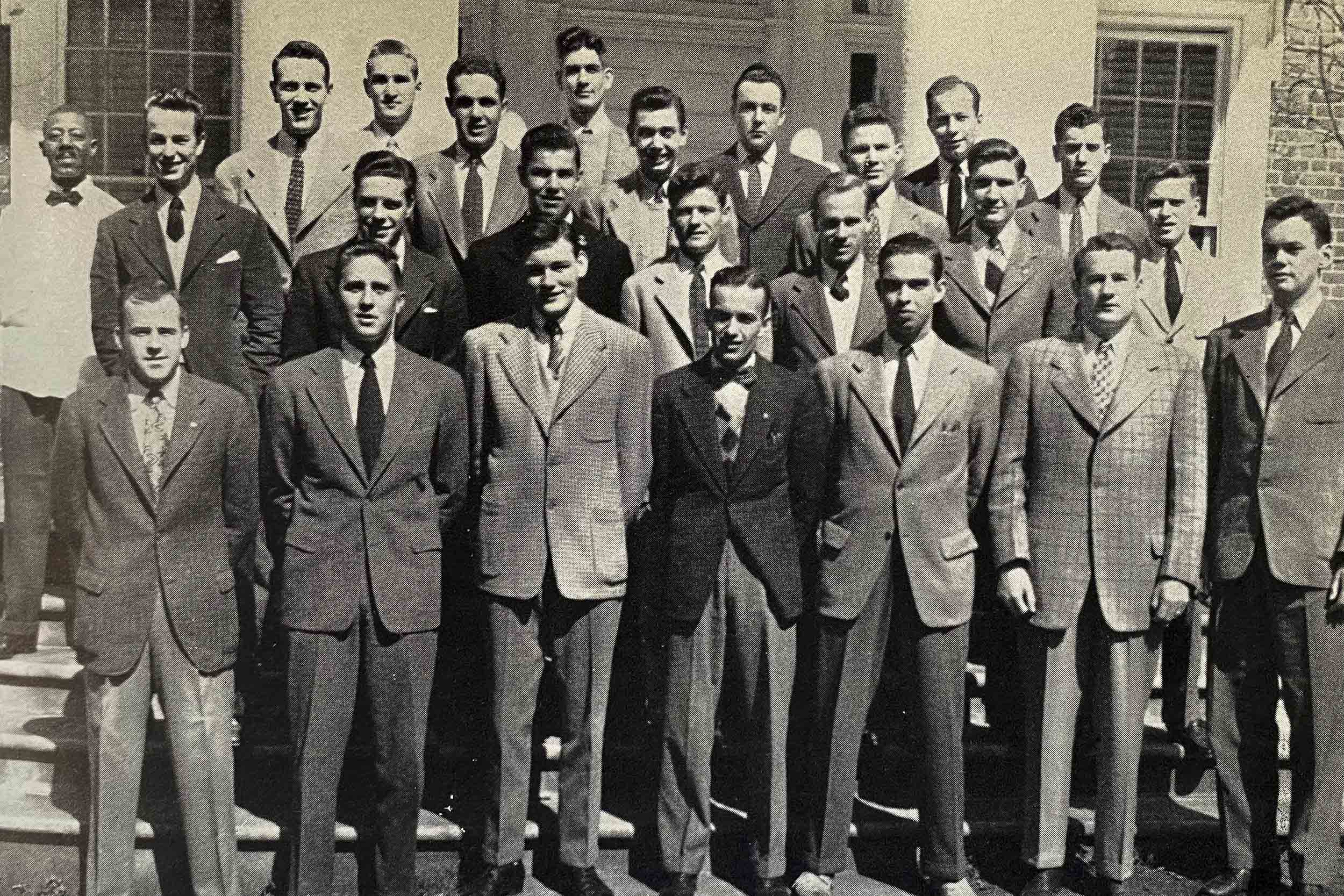 Black and white photo of a group of men standing together on 4 steps posing for a group photo