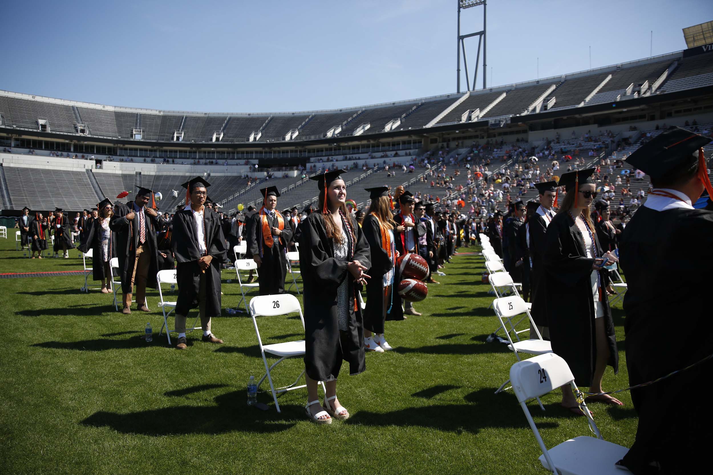 UVA Graduates standing up in front of their socially distanced chairs