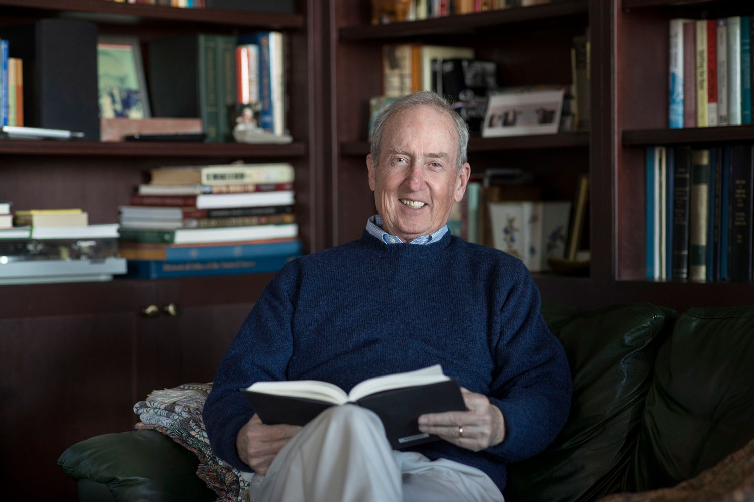 George Gilliam sits in a chair reading a book