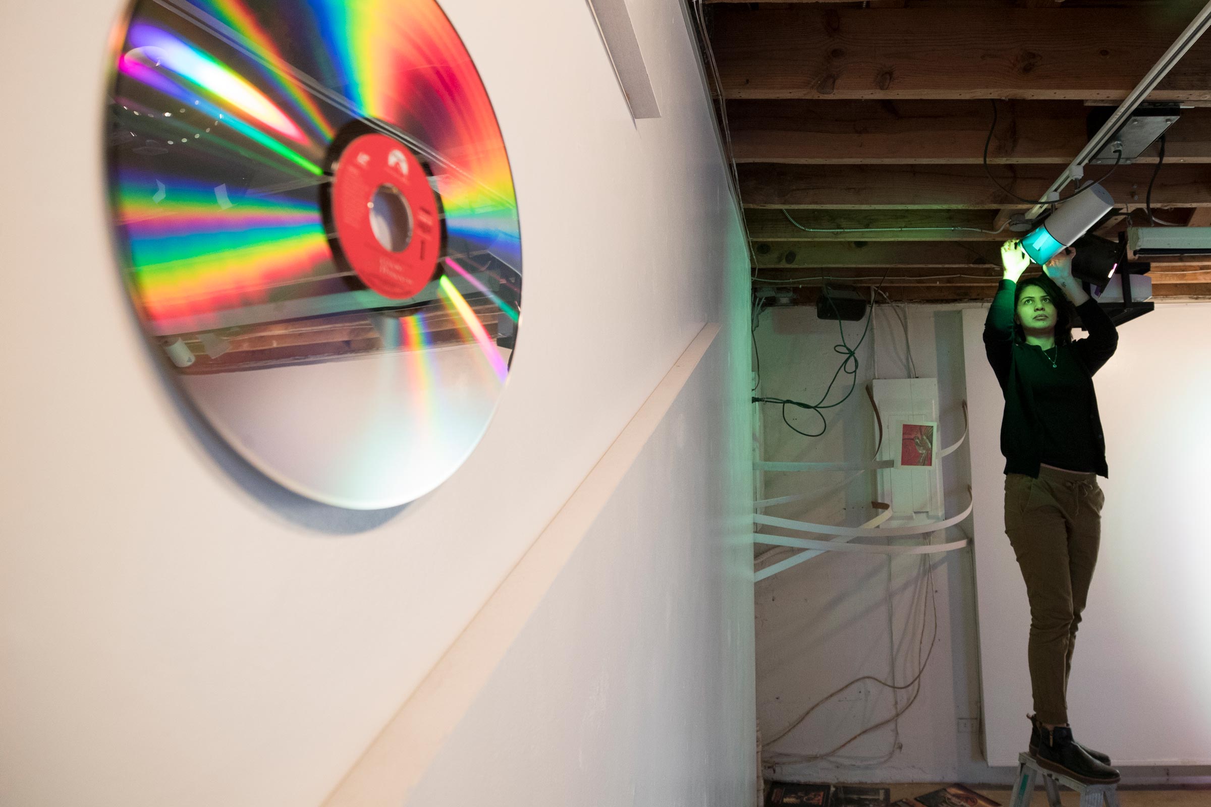 CD on a wall and a woman adjusting a blue light