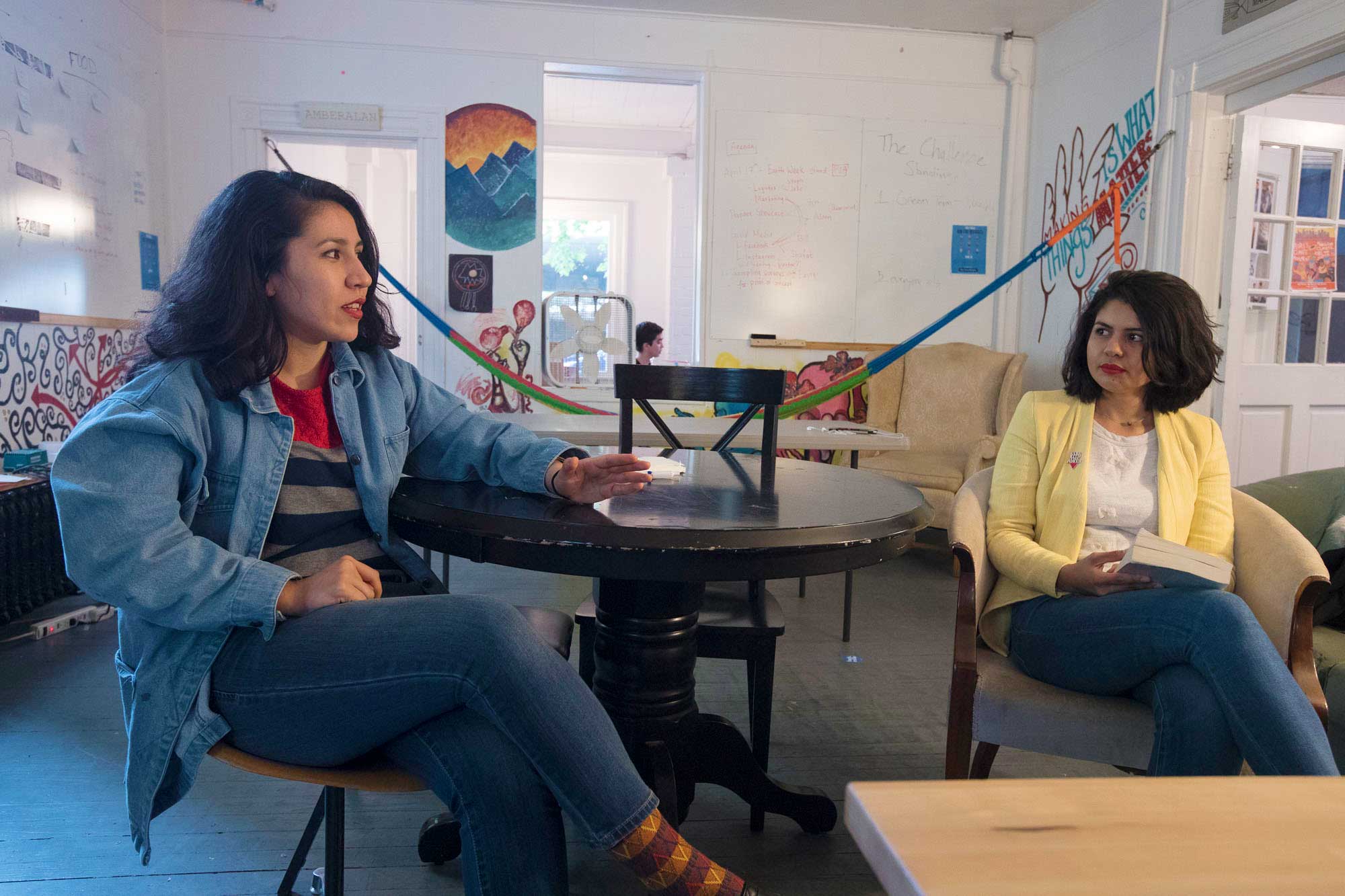 Two women sit at a round table talking