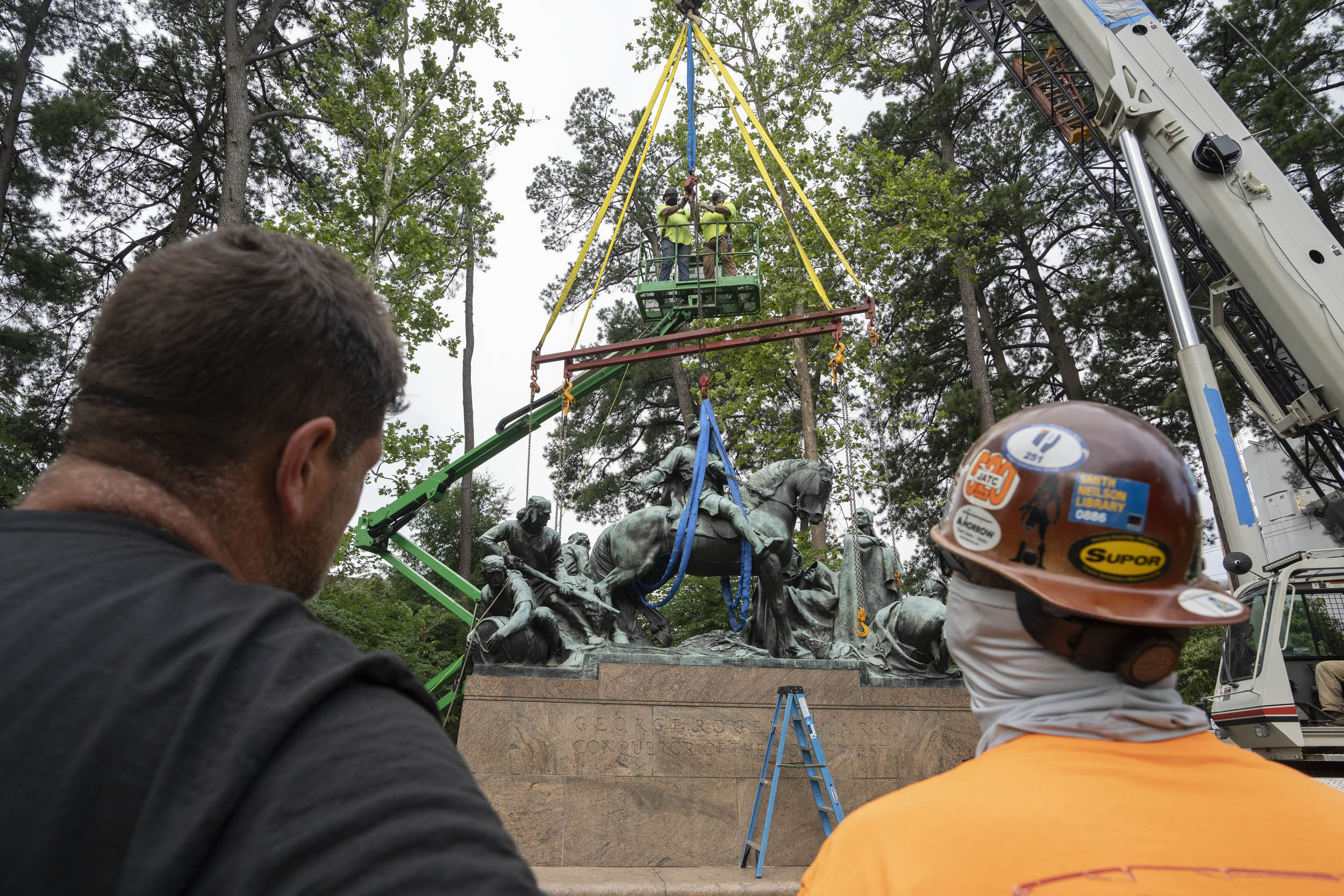 Construction workers watch at the clark statue gets removed