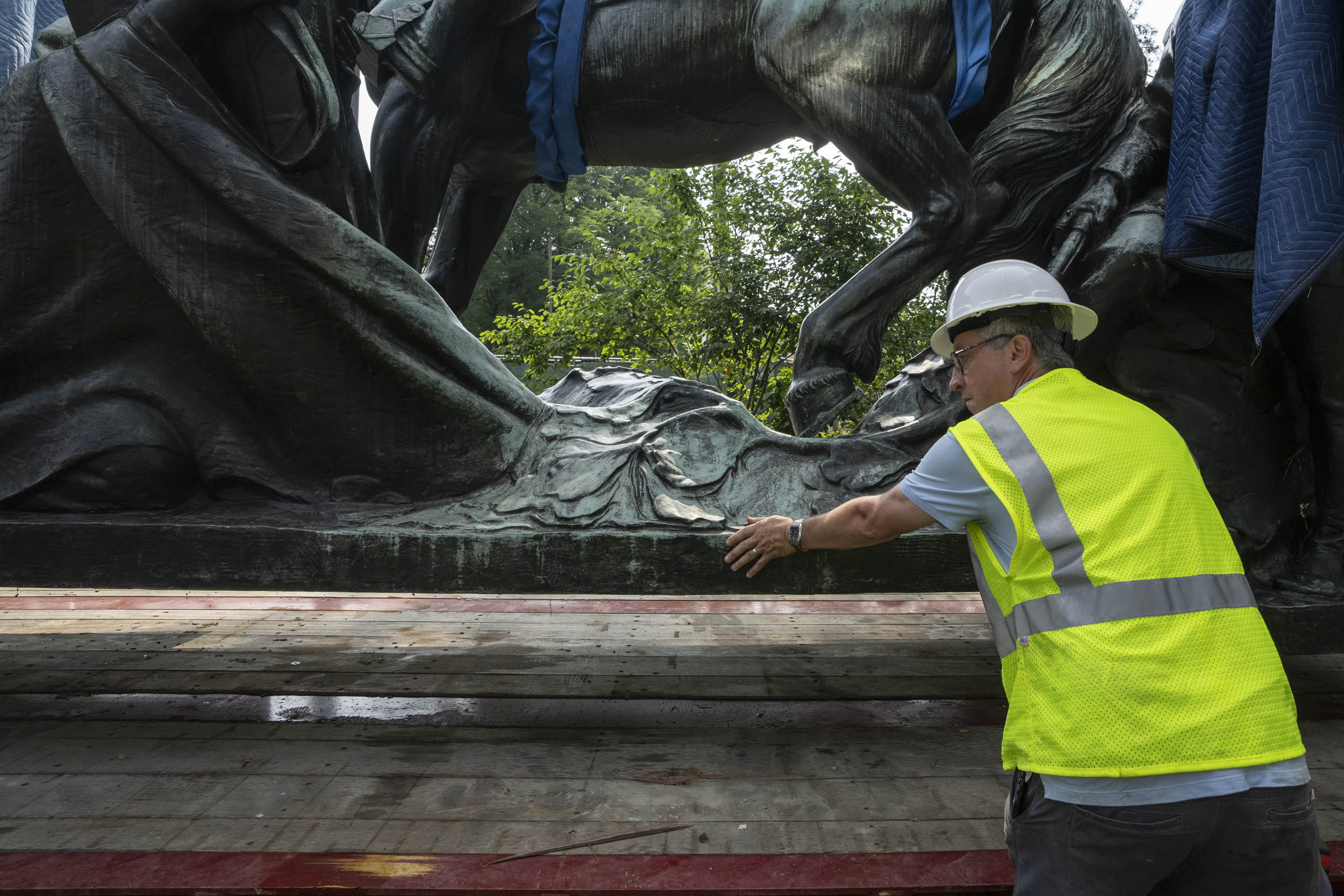Construction worker guiding statue as it gets placed on a flatbed truck