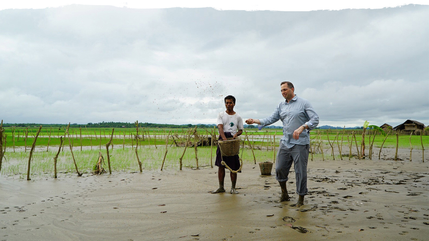 Two men in a muddy rice field working