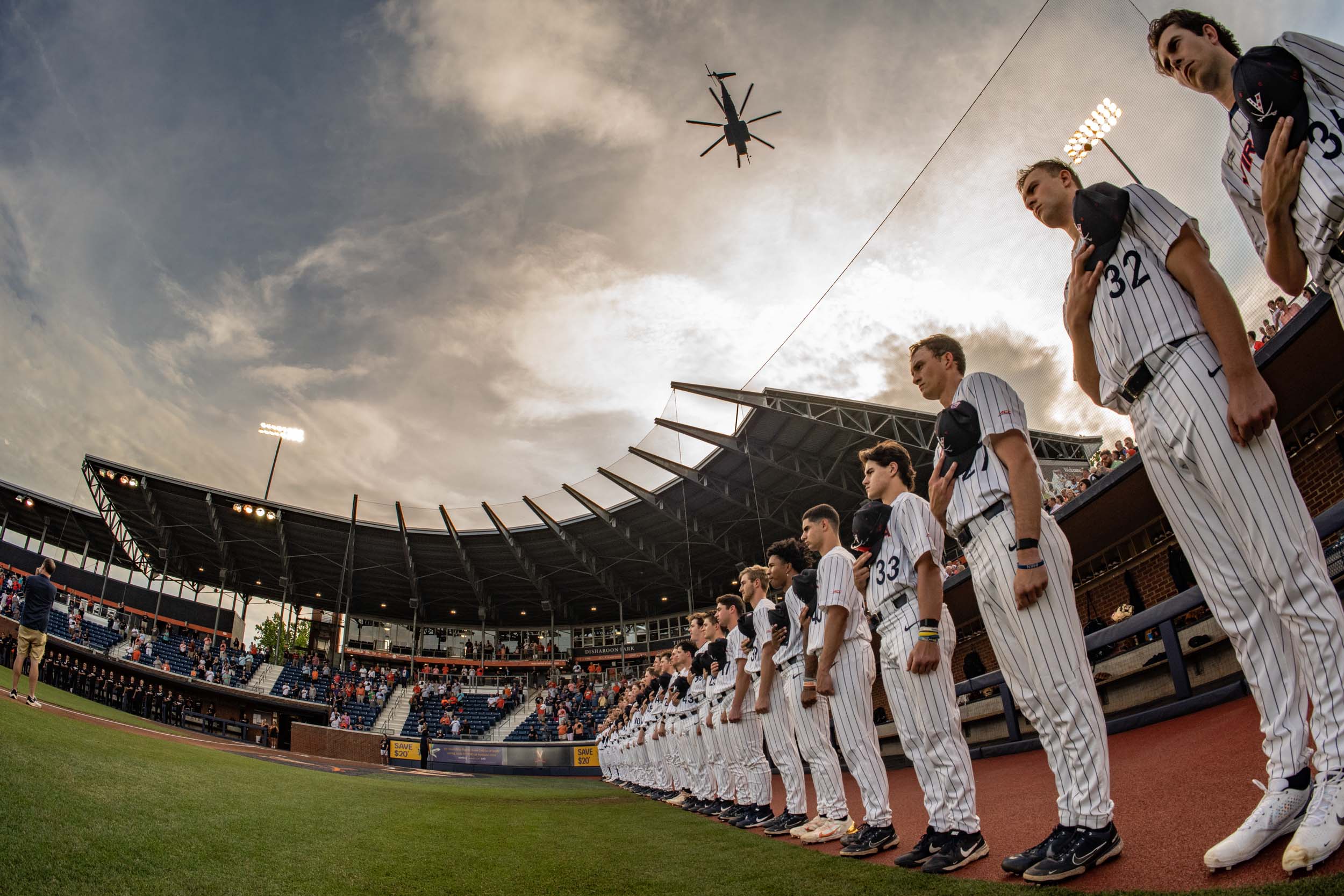 A fisheye look up at the U V A baseball team as they stand lined up for the national anthem and a heliocopter flys over