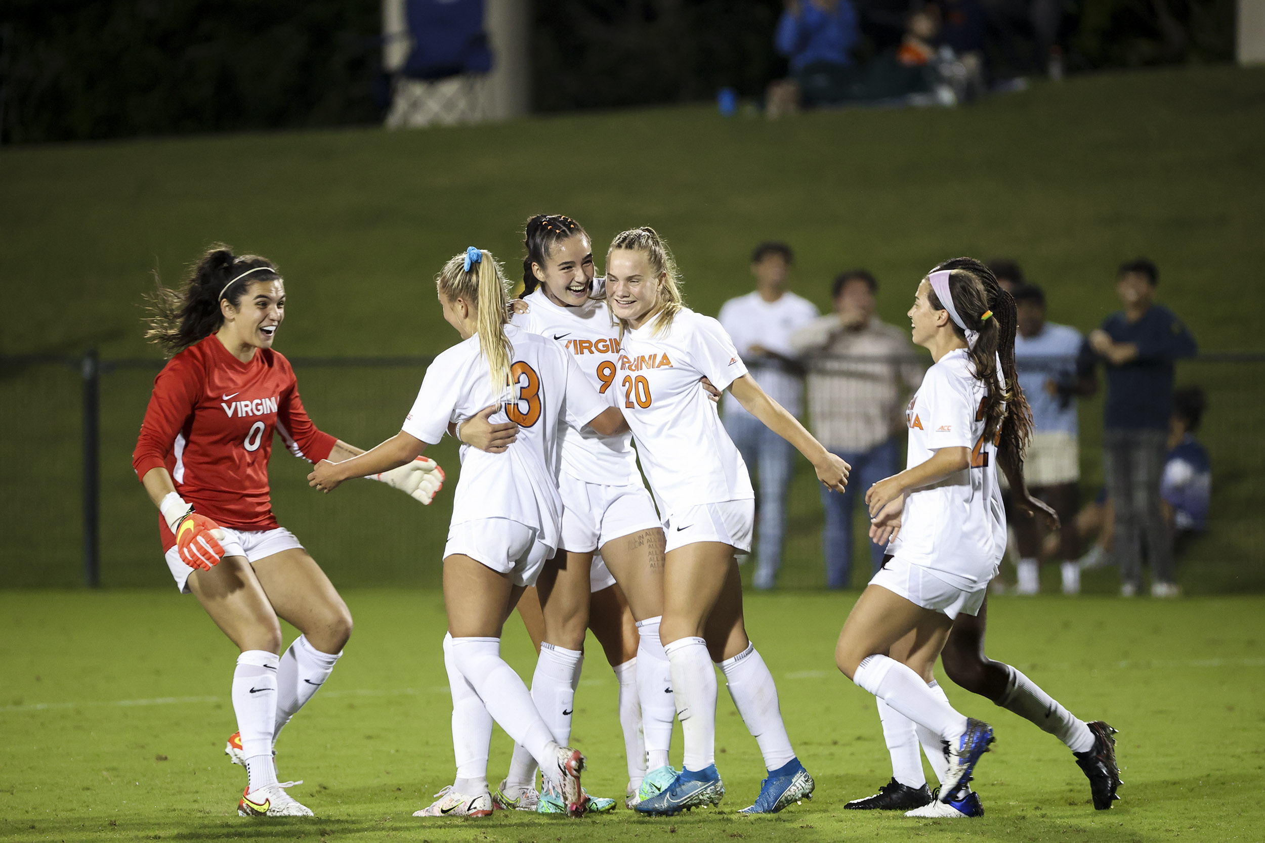 UVA Womens soccer team embracing each other on the field after winning game