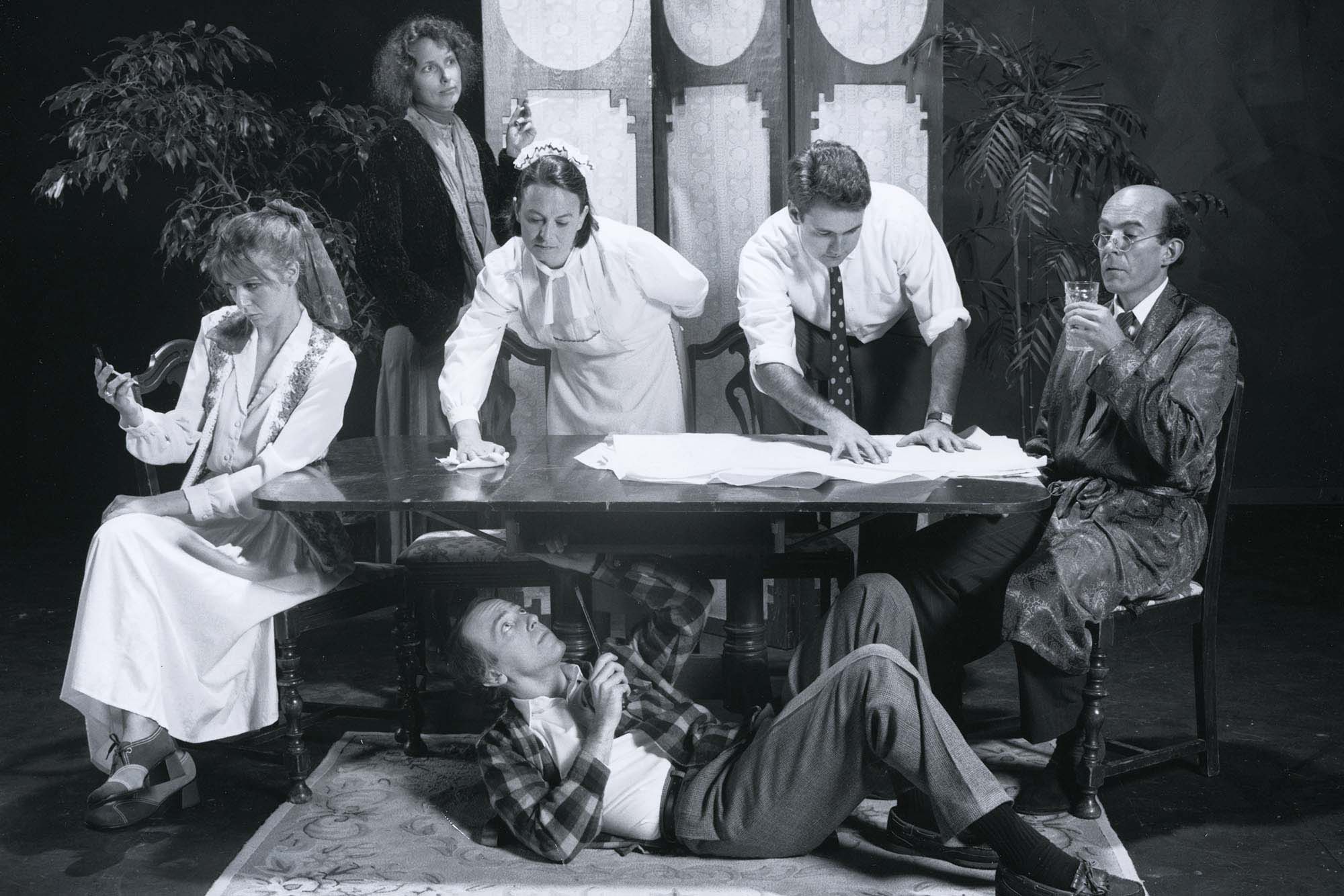 Cast on stage at a table during a play