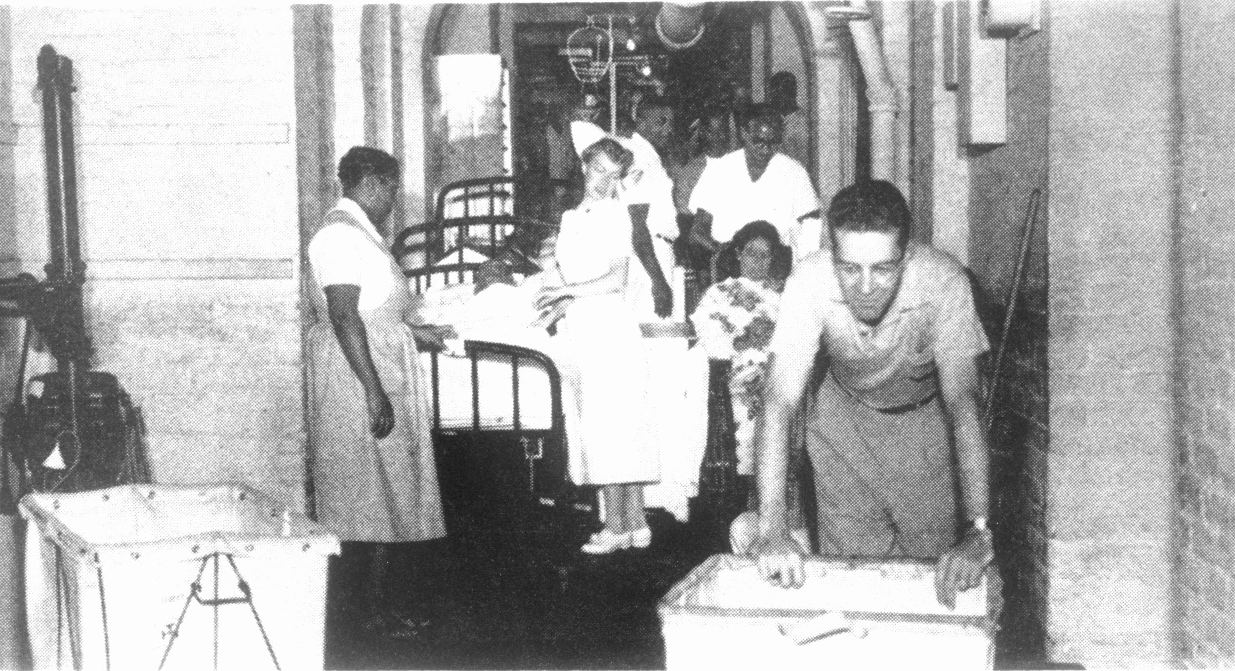 Black and White photo of hospital workers and patients in a hallway