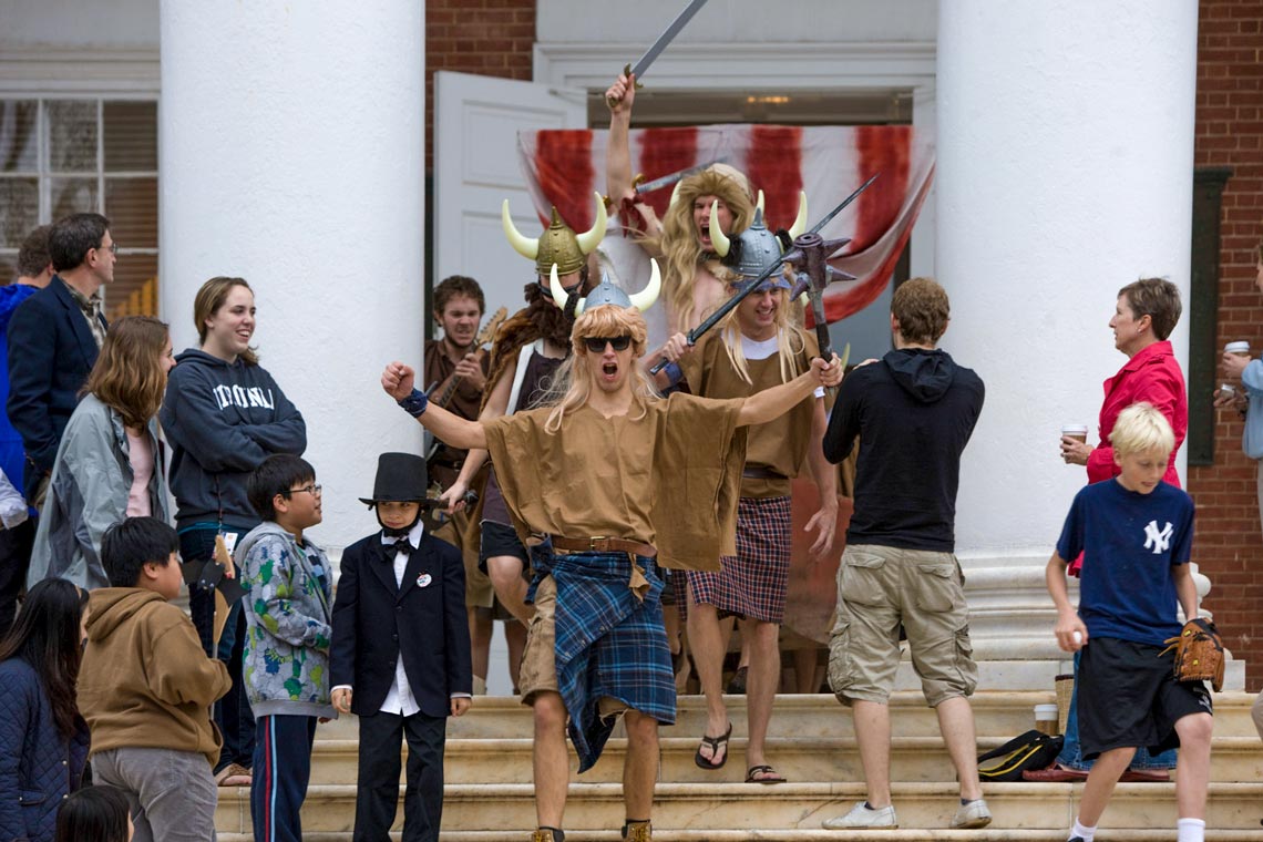 Several male college students dressed in viking costumes descend a staircase