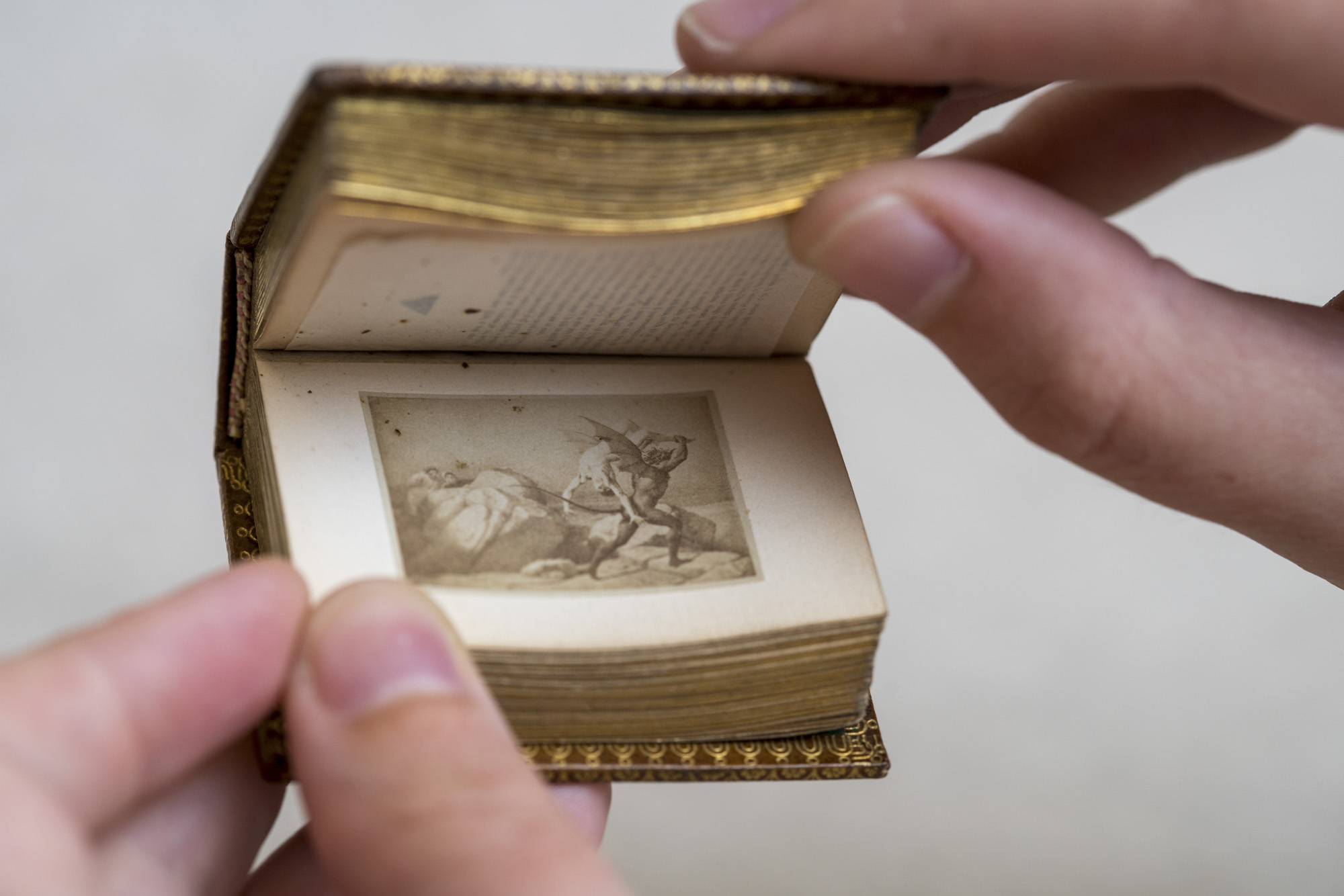 person flipping through the pages of an old mini book
