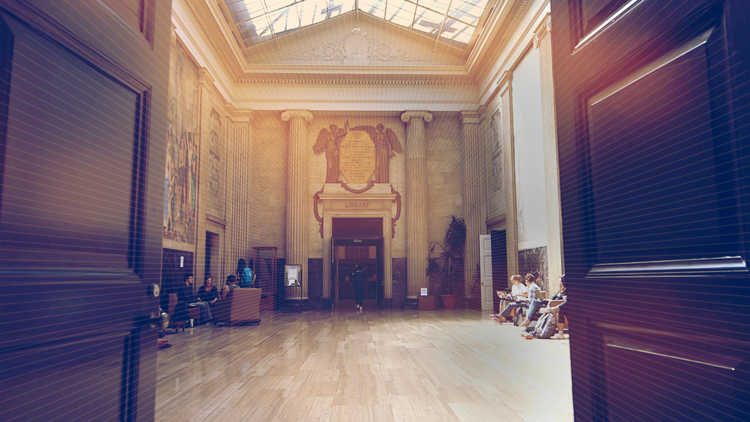 Doors opening to see a room with floor to ceiling murals and people sitting in chairs on each side of the room