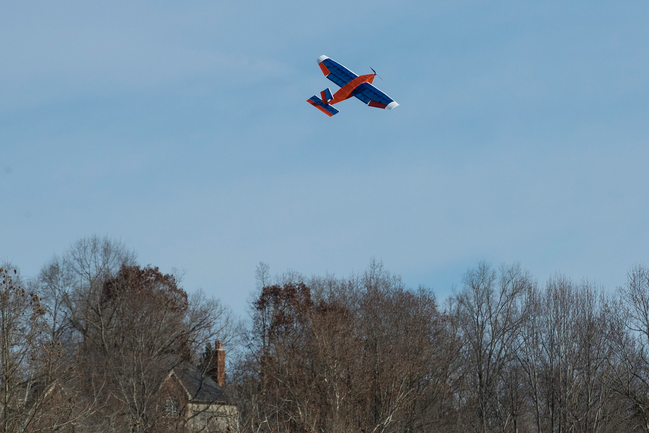 Orange, blue, and white plane flying in the air