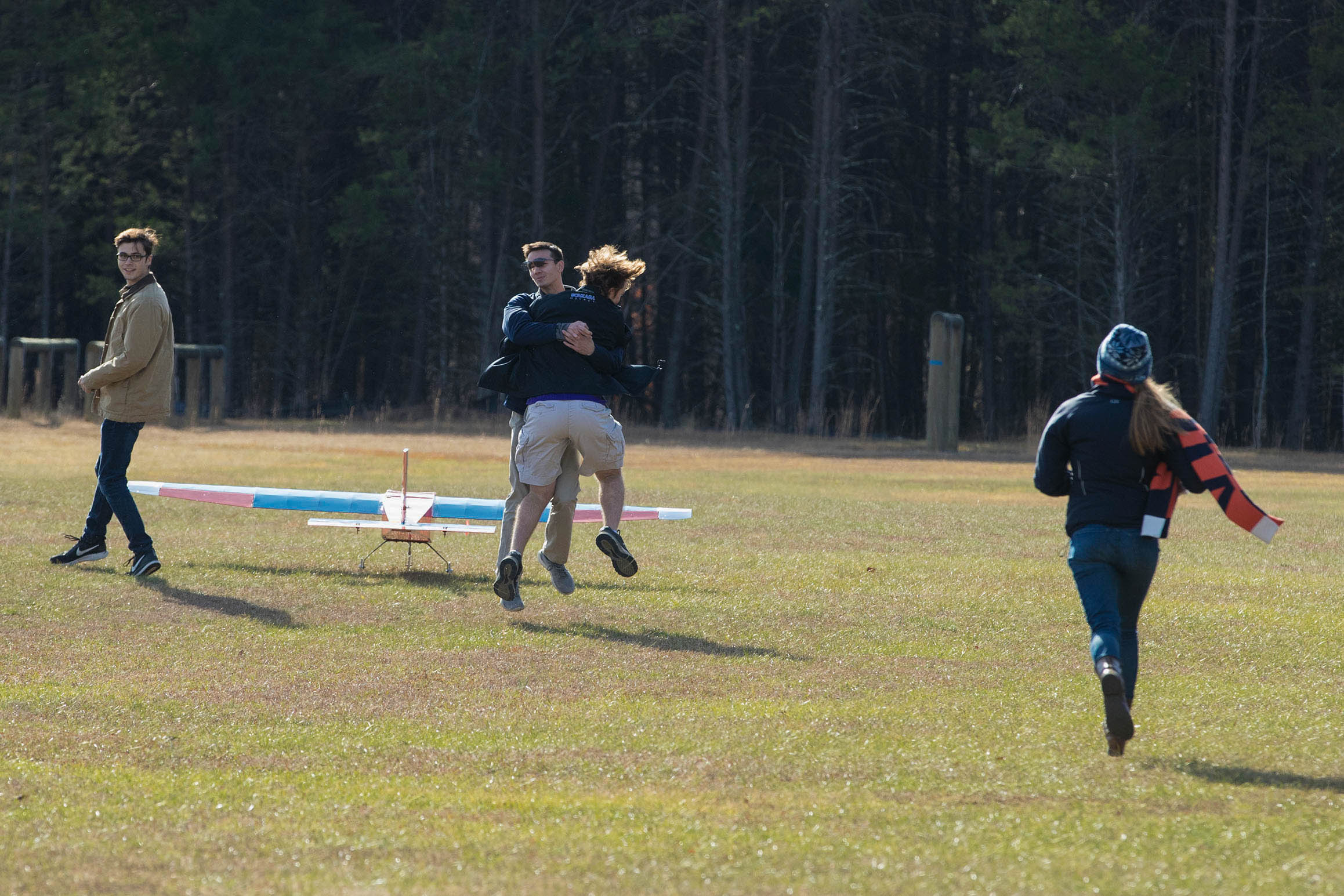 Ryan Keough and Andrew Metro hug in mid-air and Jack Shea, left, and Grace Vidlak run onto the field after a successful flight of their plane