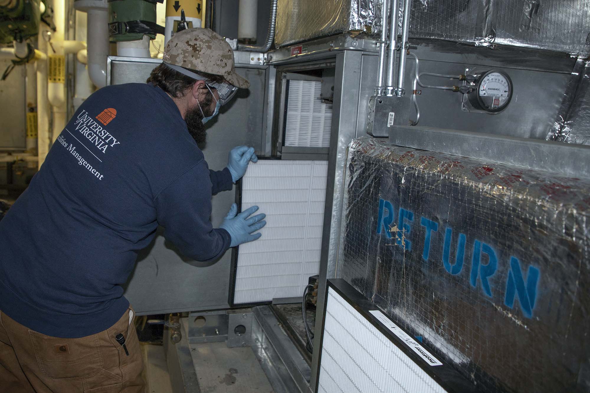 Staff member installing high-efficiency filter in the air-handler unit