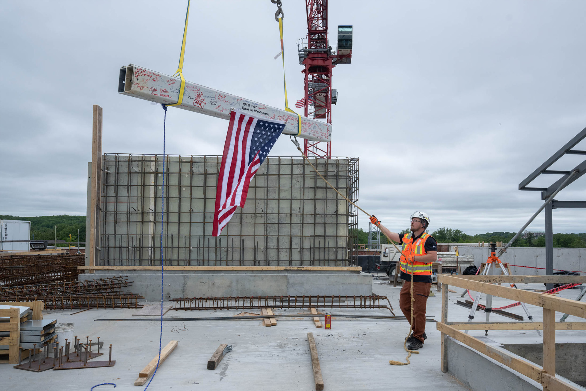 Construction worker guiding the placement of the signed beam.