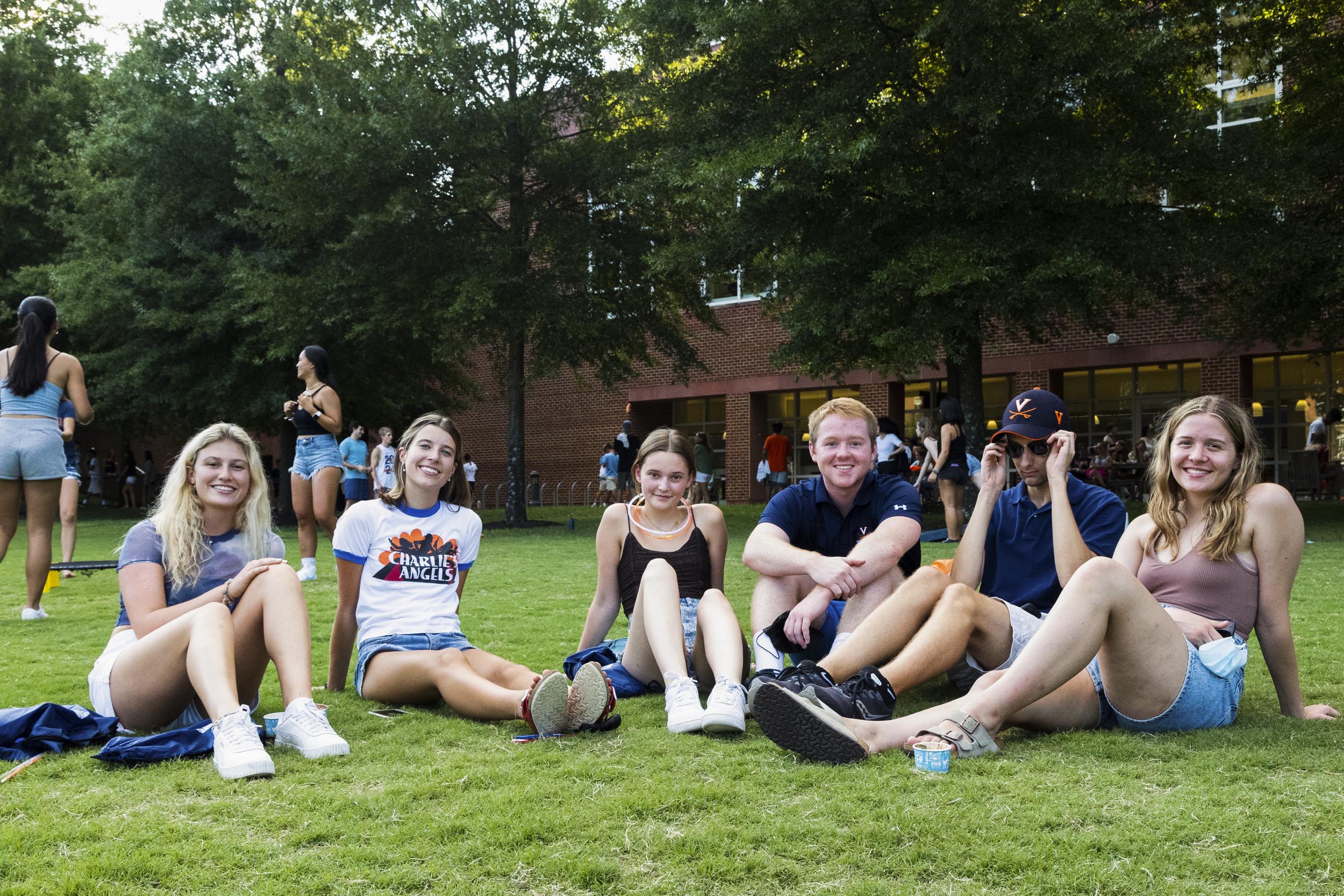 Students sitting together in the grass outside of a dorm building on Grounds
