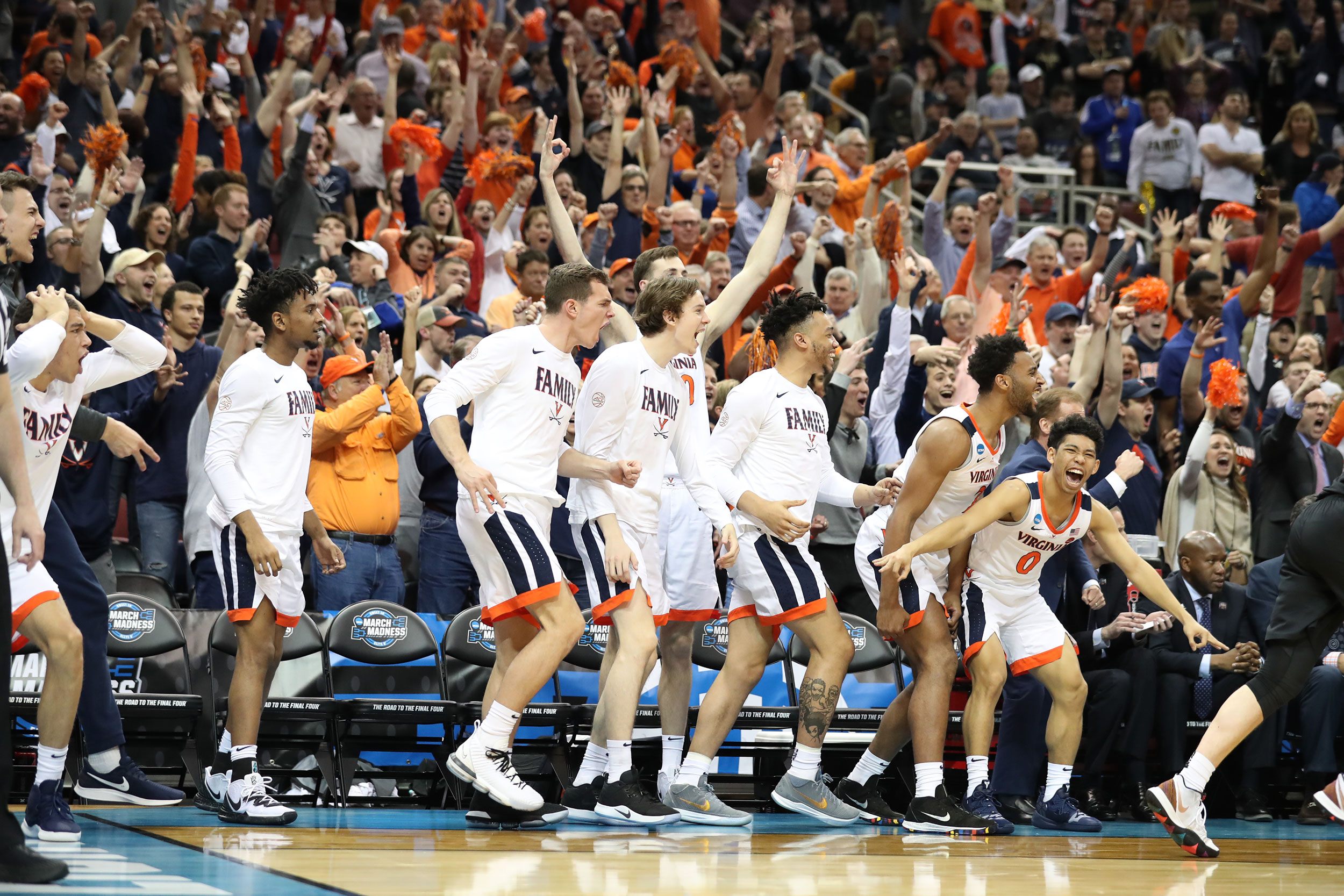 UVA basketball team erupting in celebration on the side of the court 