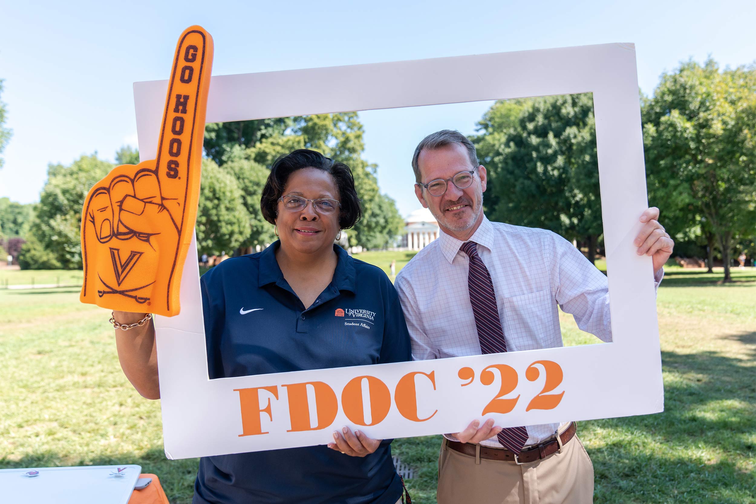Robyn Hadley wears a foam finger reading Go Hoos while she and Ian Baucom hold a frame reading FDOC '22