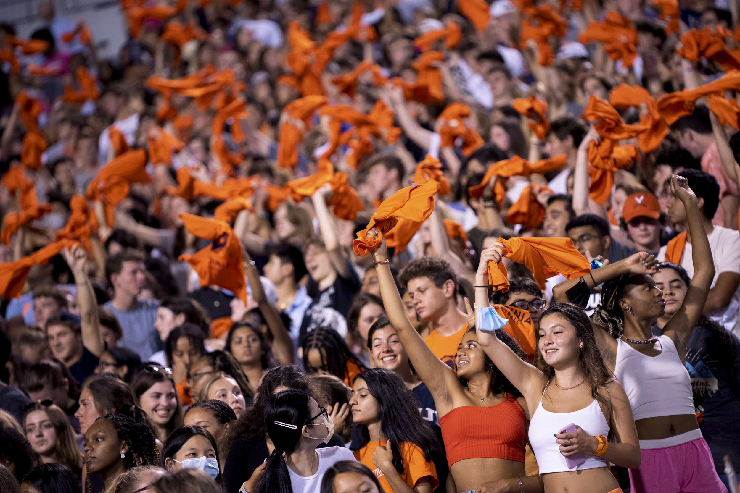 Crowd of students waving orange towels at a football game