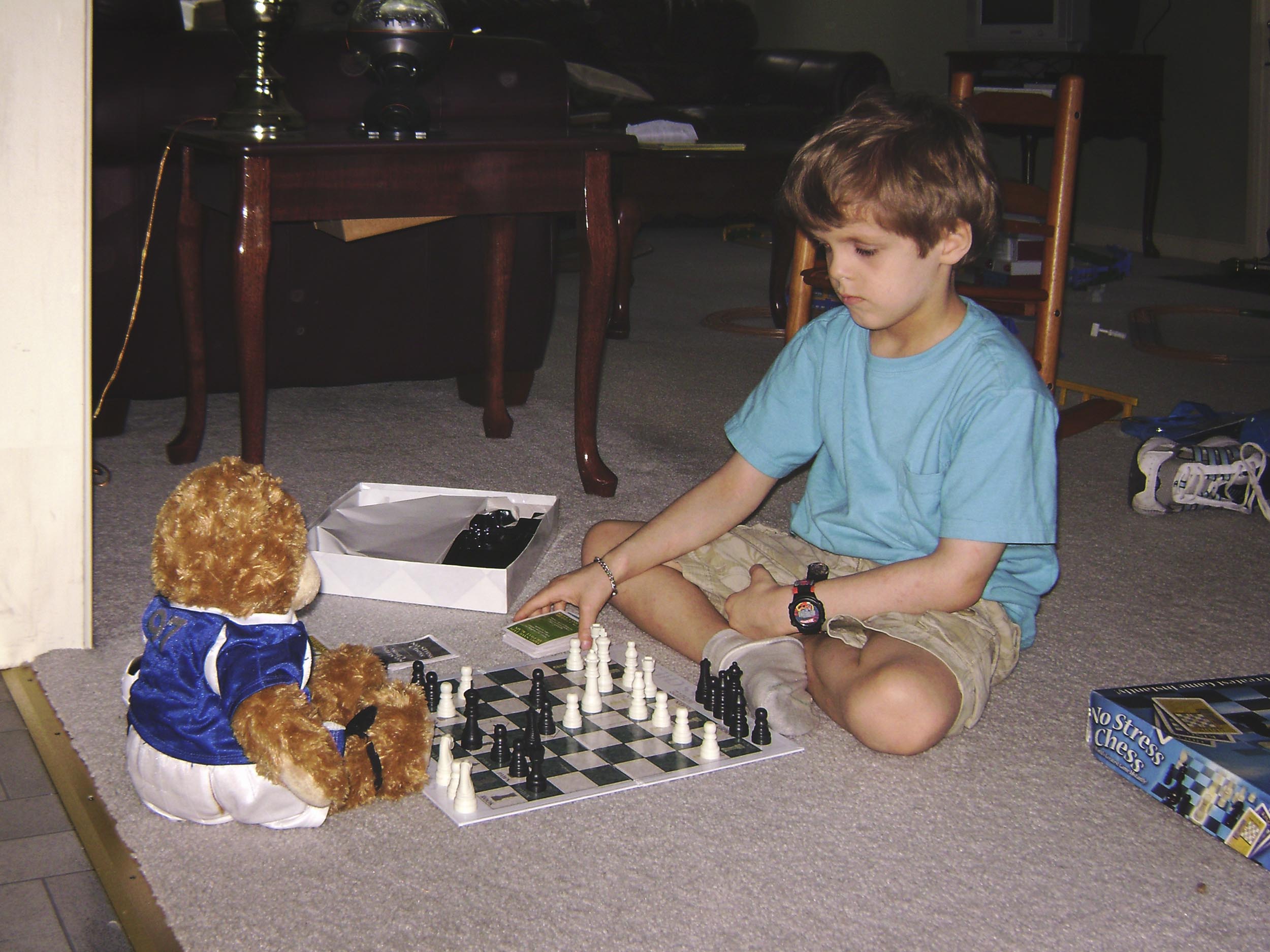Jason Morefield when he was a child sitting on the floor playing chess with a teddy bear