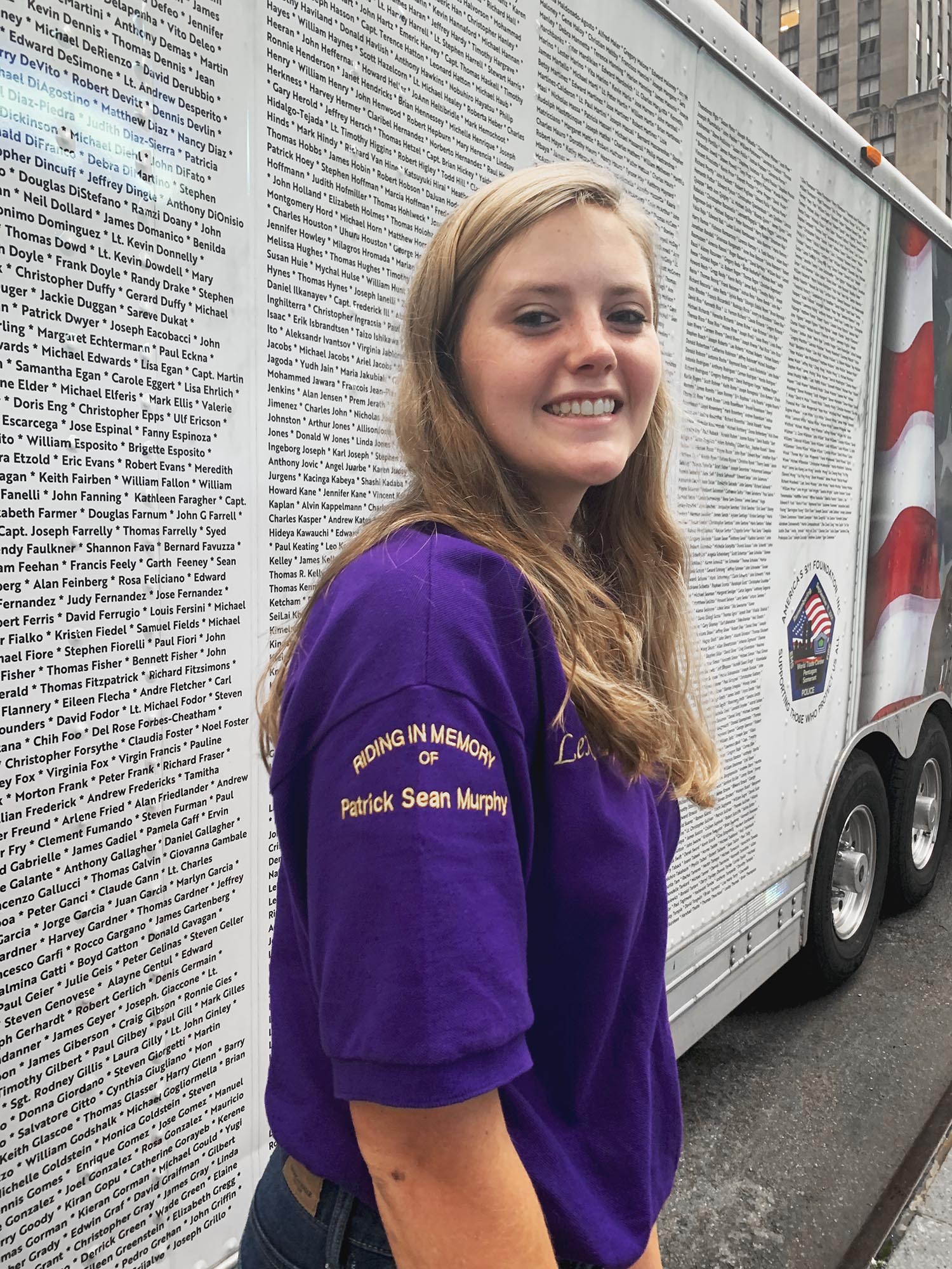 Sjurseth posing for picture showing her shirt sleeve that reads: Riding in Memory of Patrick Sean Murphy