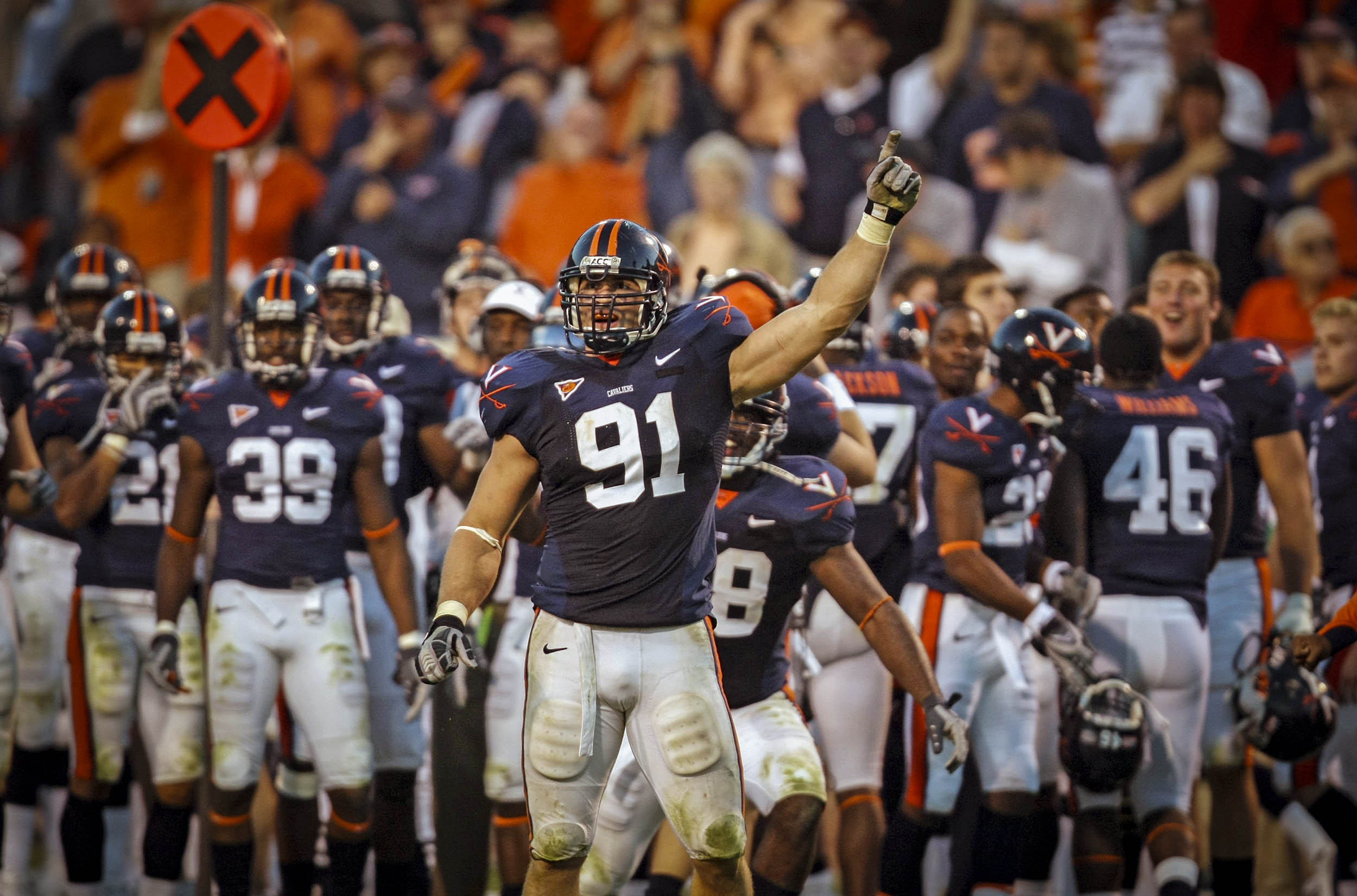 UVA football team standing together with Chris Long in front of everyone whit is left arm raised in the air